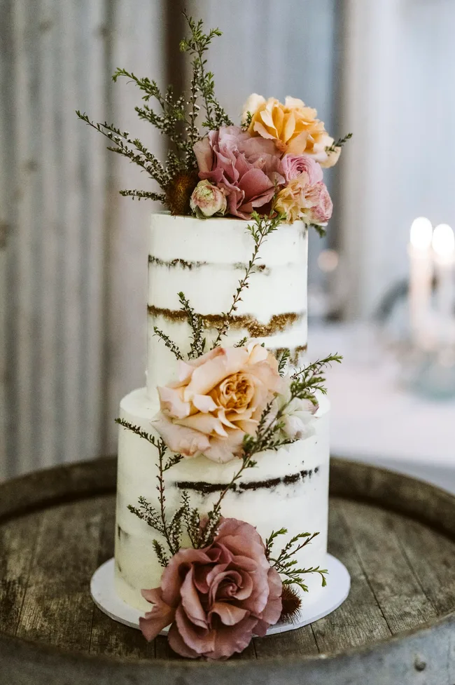 A wedding cake adorned with flowers and sprigs