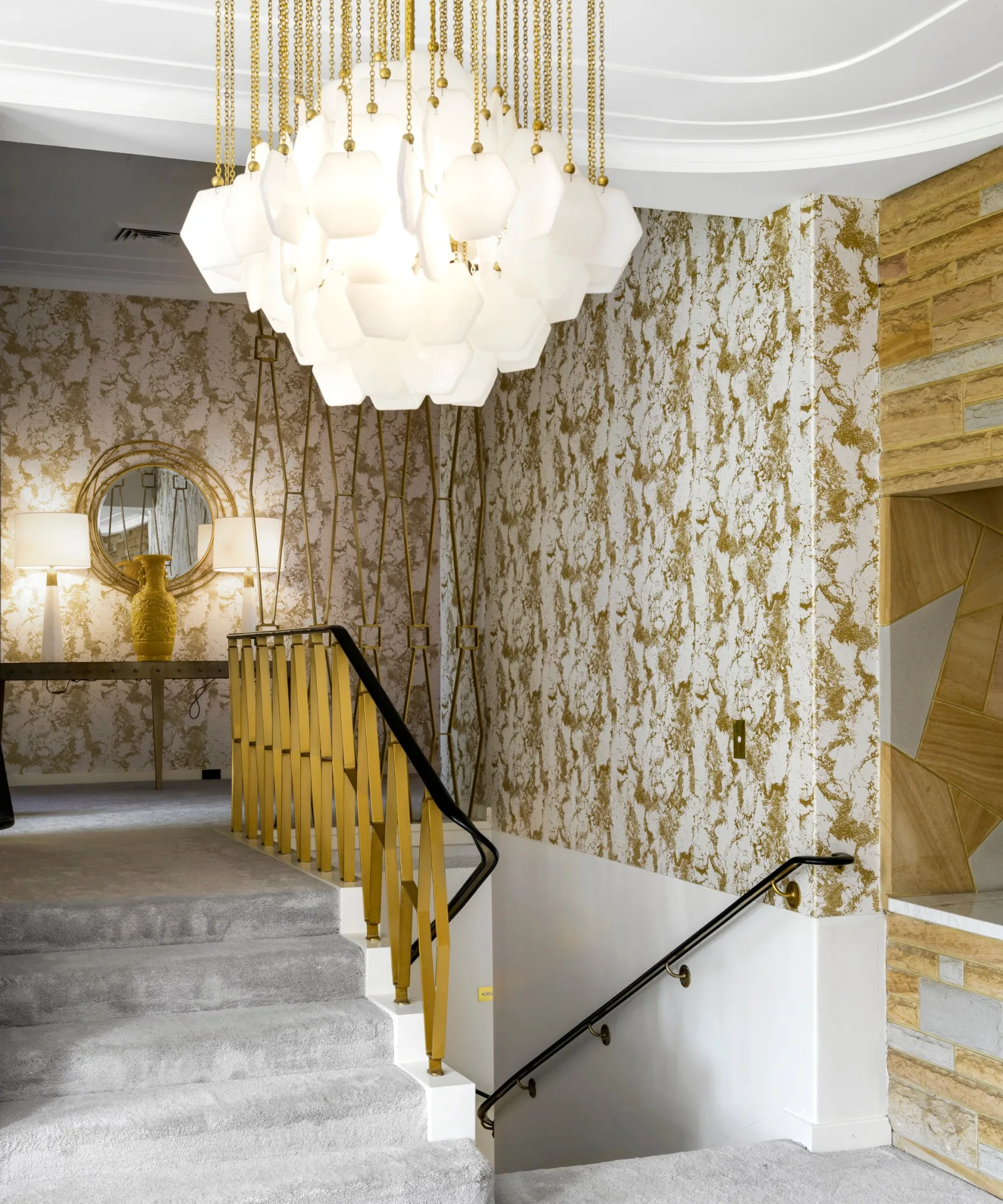 Staircase with chandelier and gold wallpaper