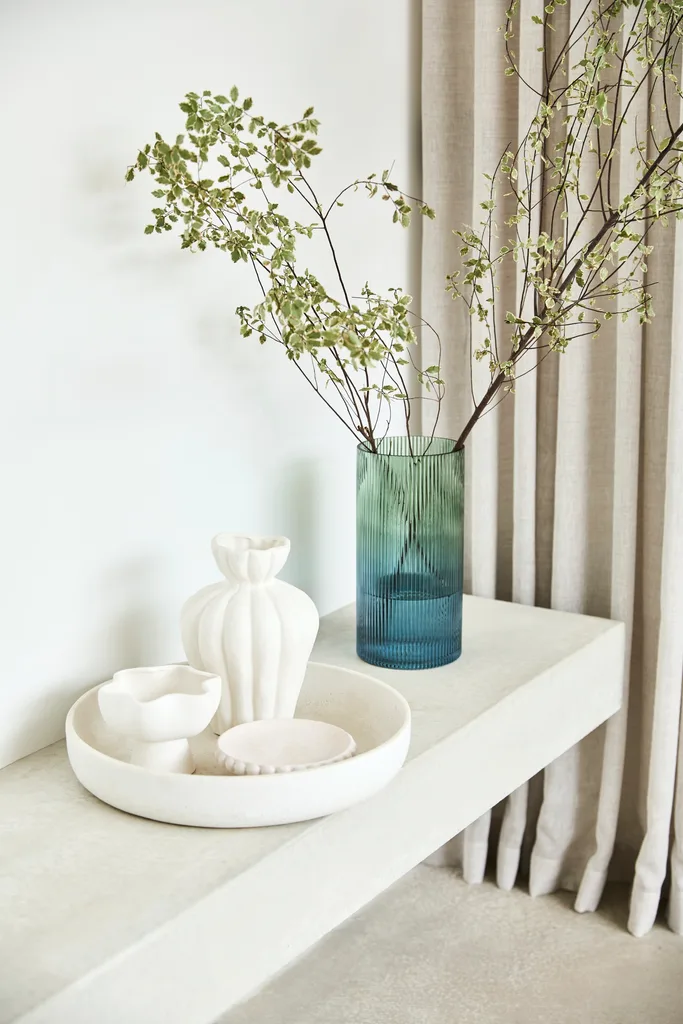 white bowls and vases next to a blue glass vase