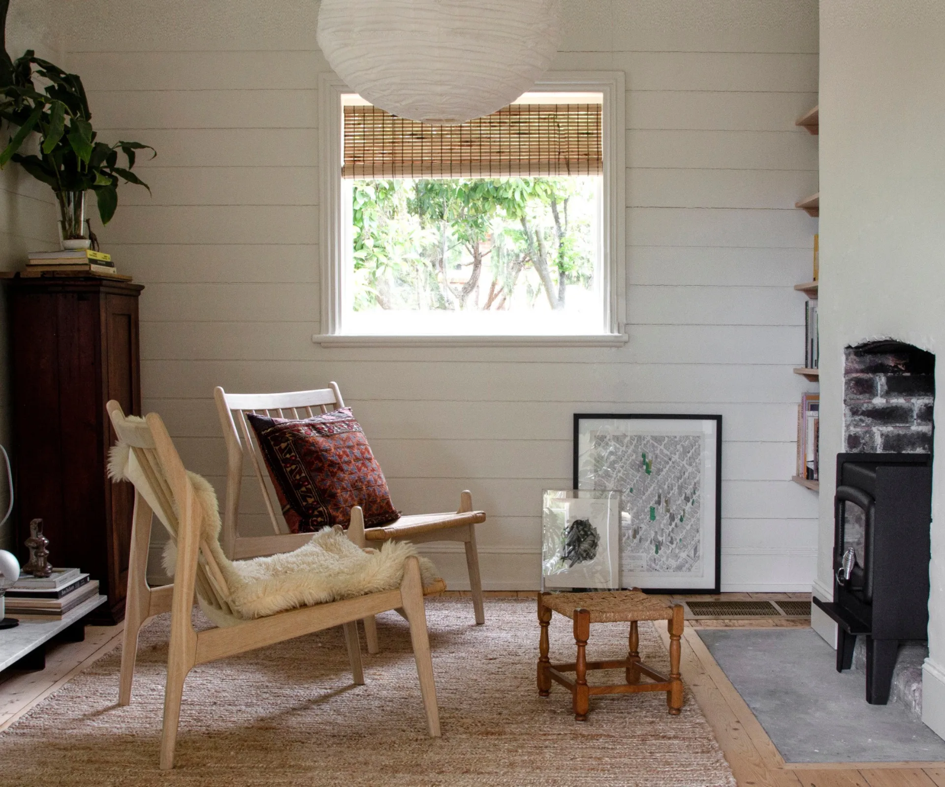 A minimalist sitting room with a paper lantern pendant light and a woodheater