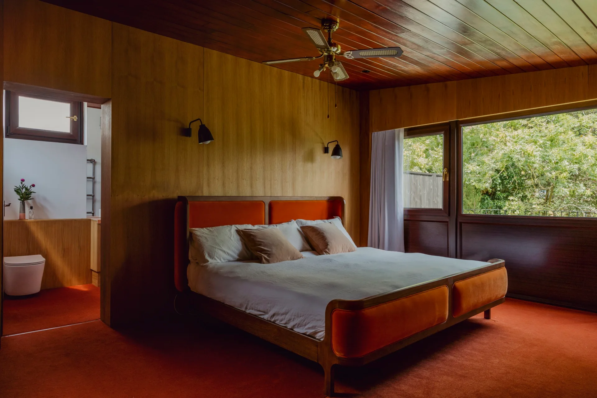 A large bedroom with timber panelling and orange carpet