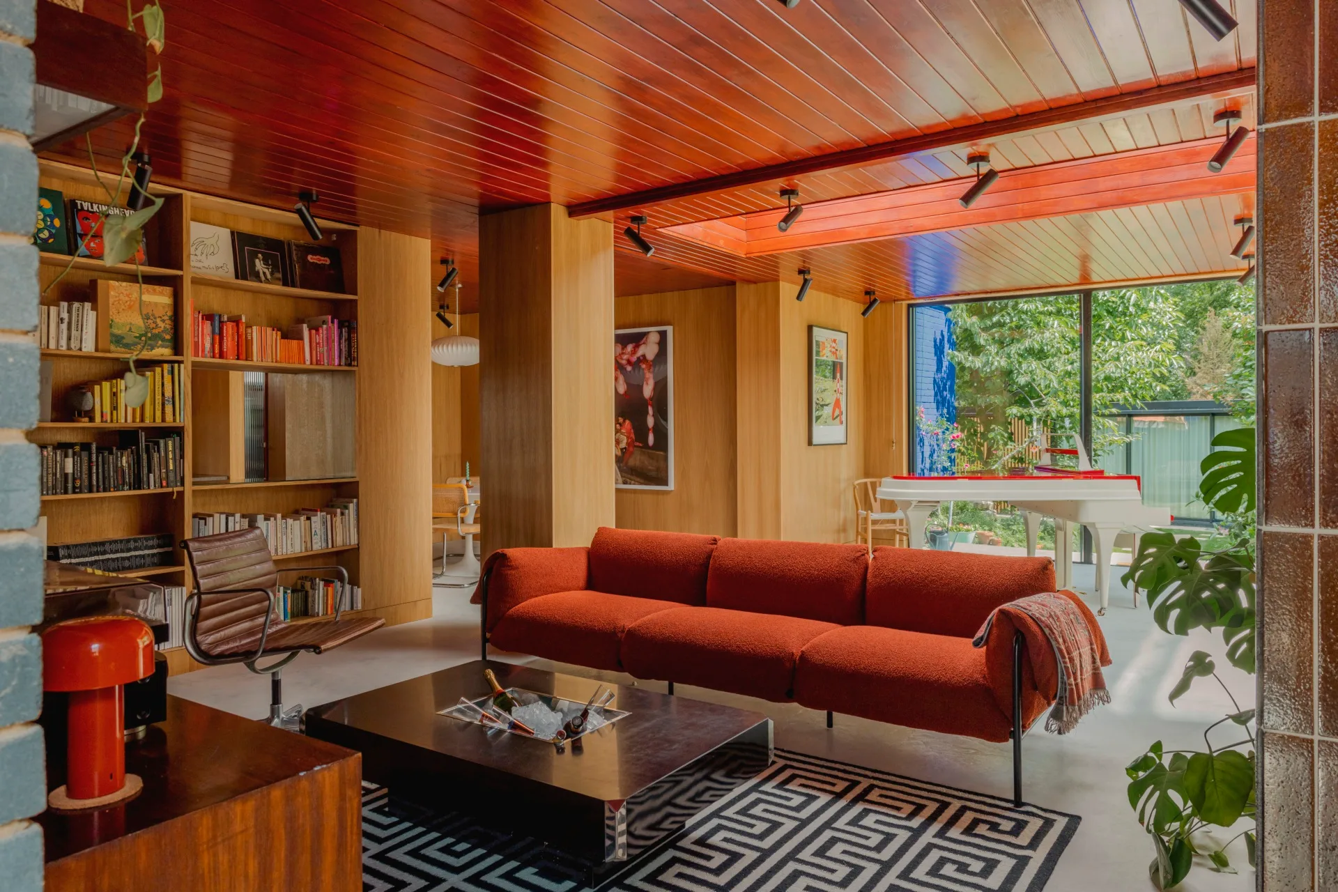 A mid-century lounge area with a geometric rug and built-in bookshelf