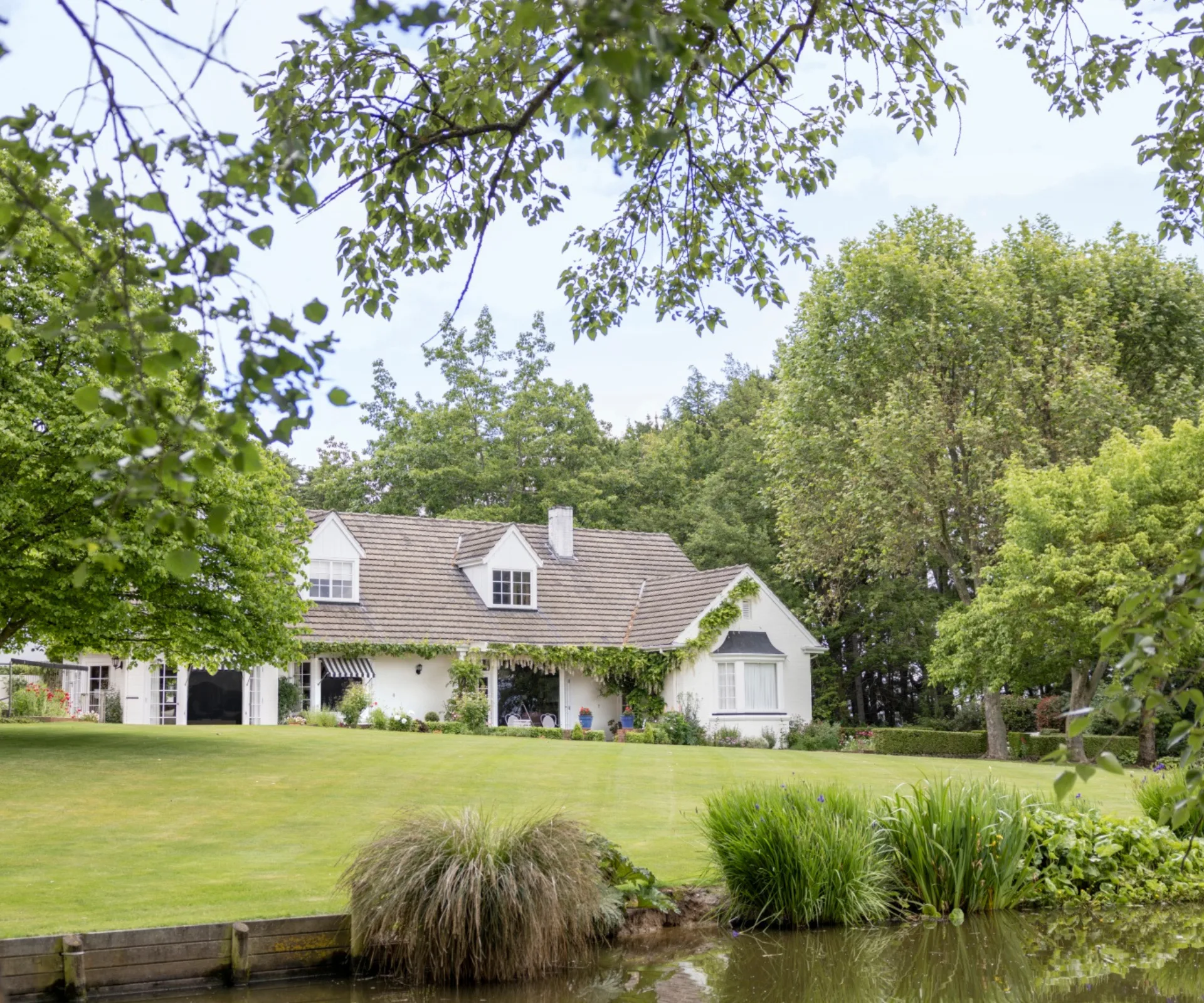 A white homestead by a lake and rolling lawns in New Zealand