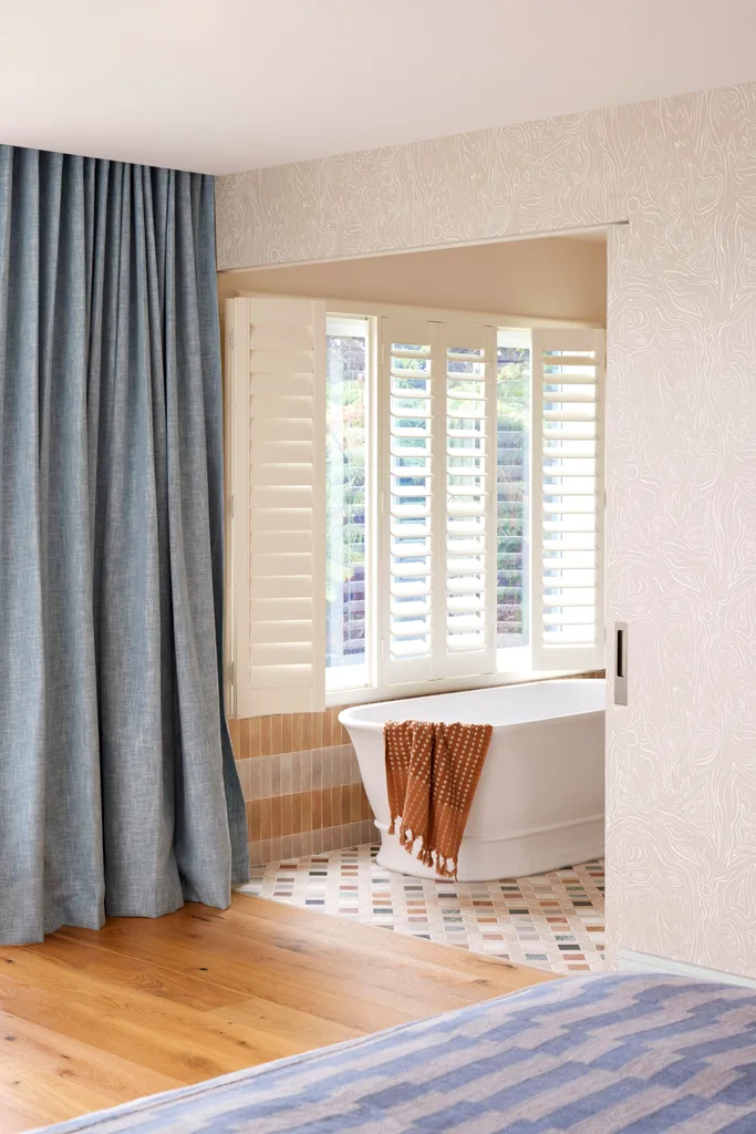 A freestanding bathtub beside large windows