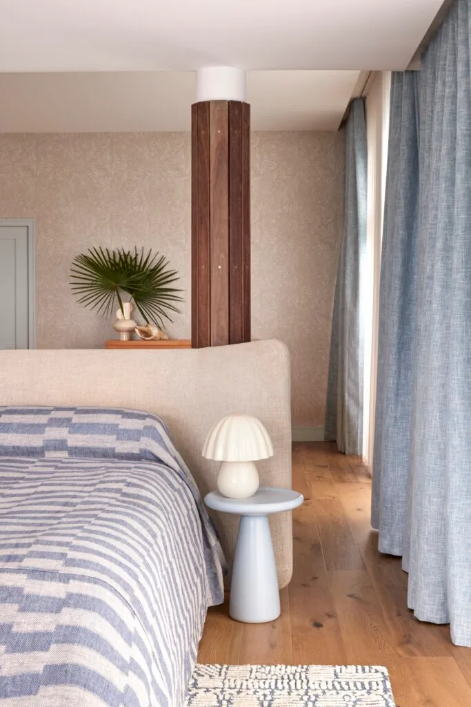 Blue toned Mediterranean-style bedroom with blue drapes, blue and grey-striped bedding and an indoor plant