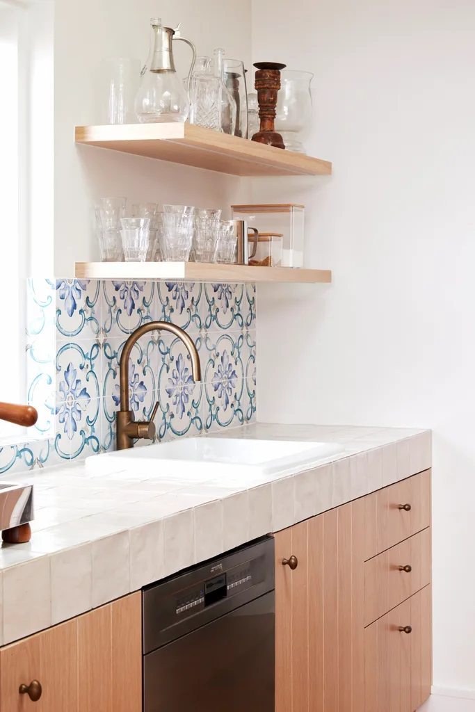 A butler's pantry with a tiled benchtop and timber floating shelving