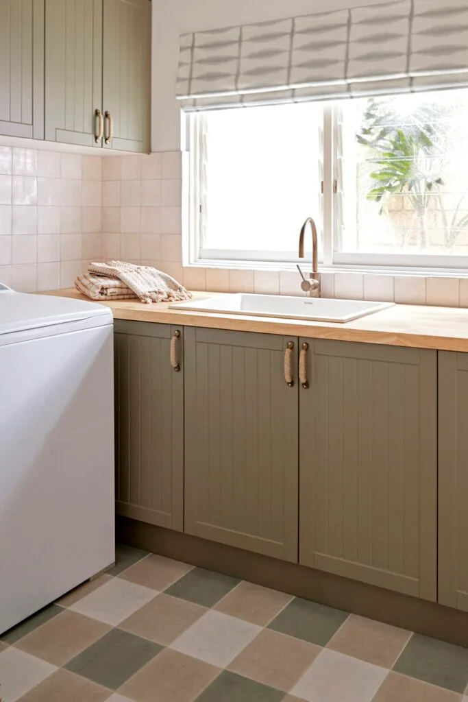 A sage green laundry with plaid-style flooring