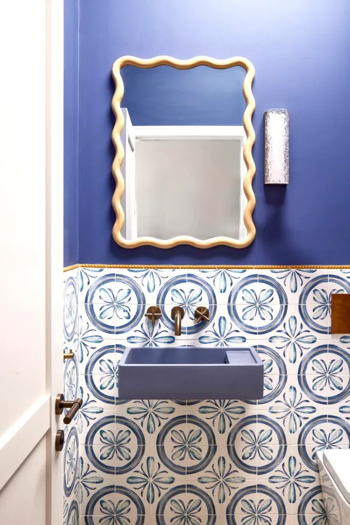 A blue powder room with a wavy mirror