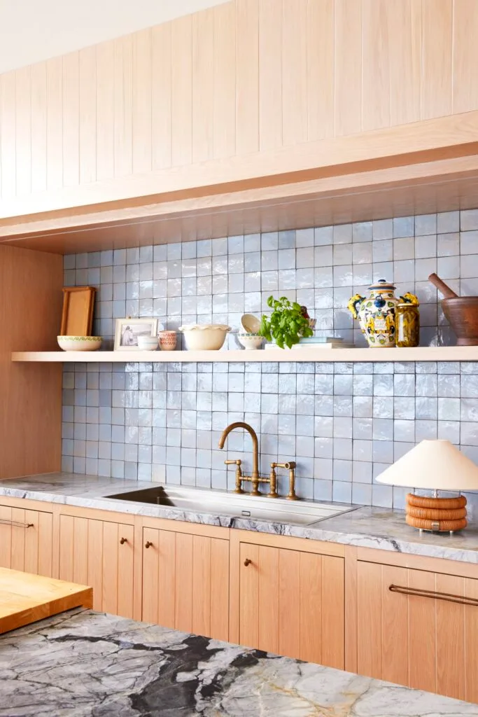 Blue tiled splashback, marble benchtops and timber cabinets in the kitchen