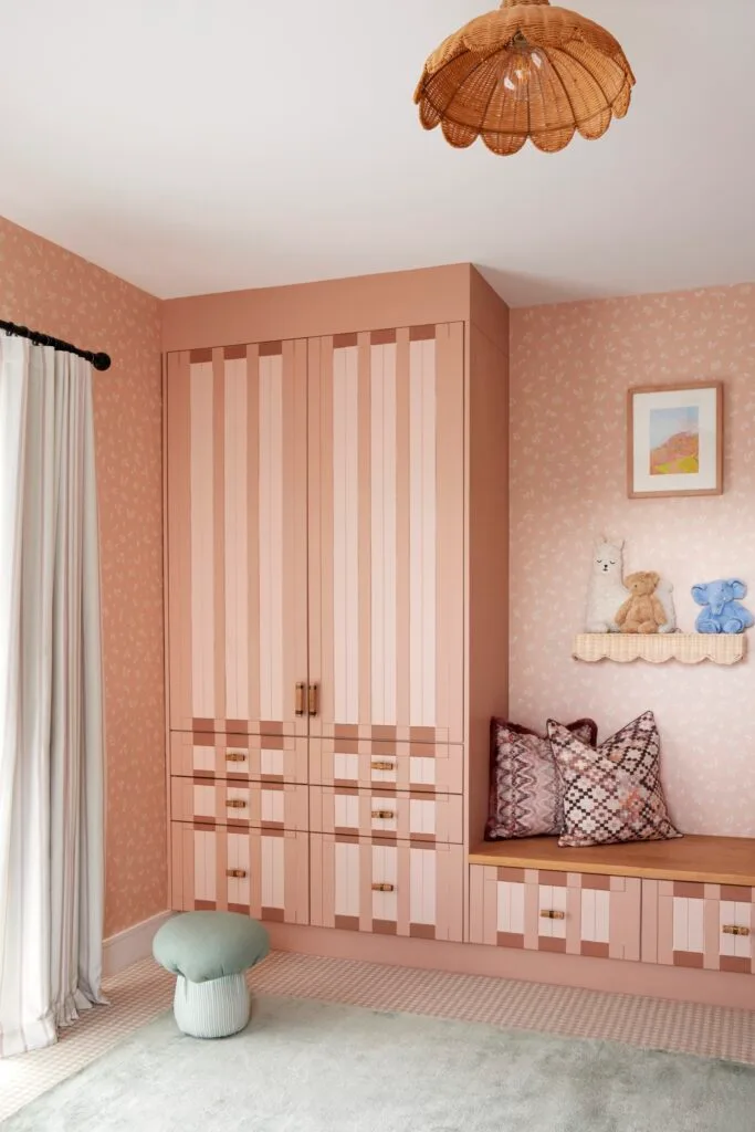 A dusty pink kids bedroom with a sage green rug