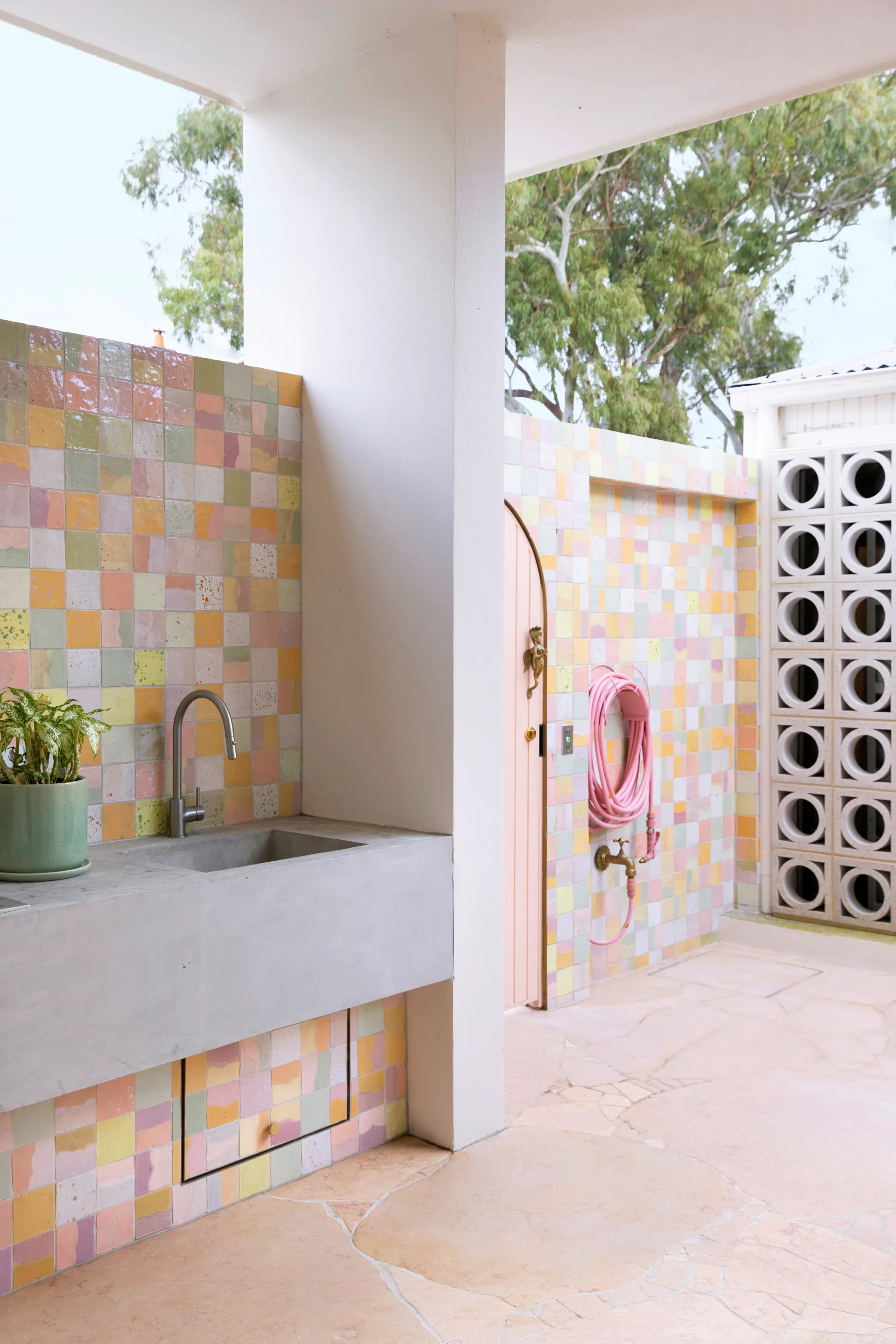 An outdoor sink with a multicoloured tiled wall