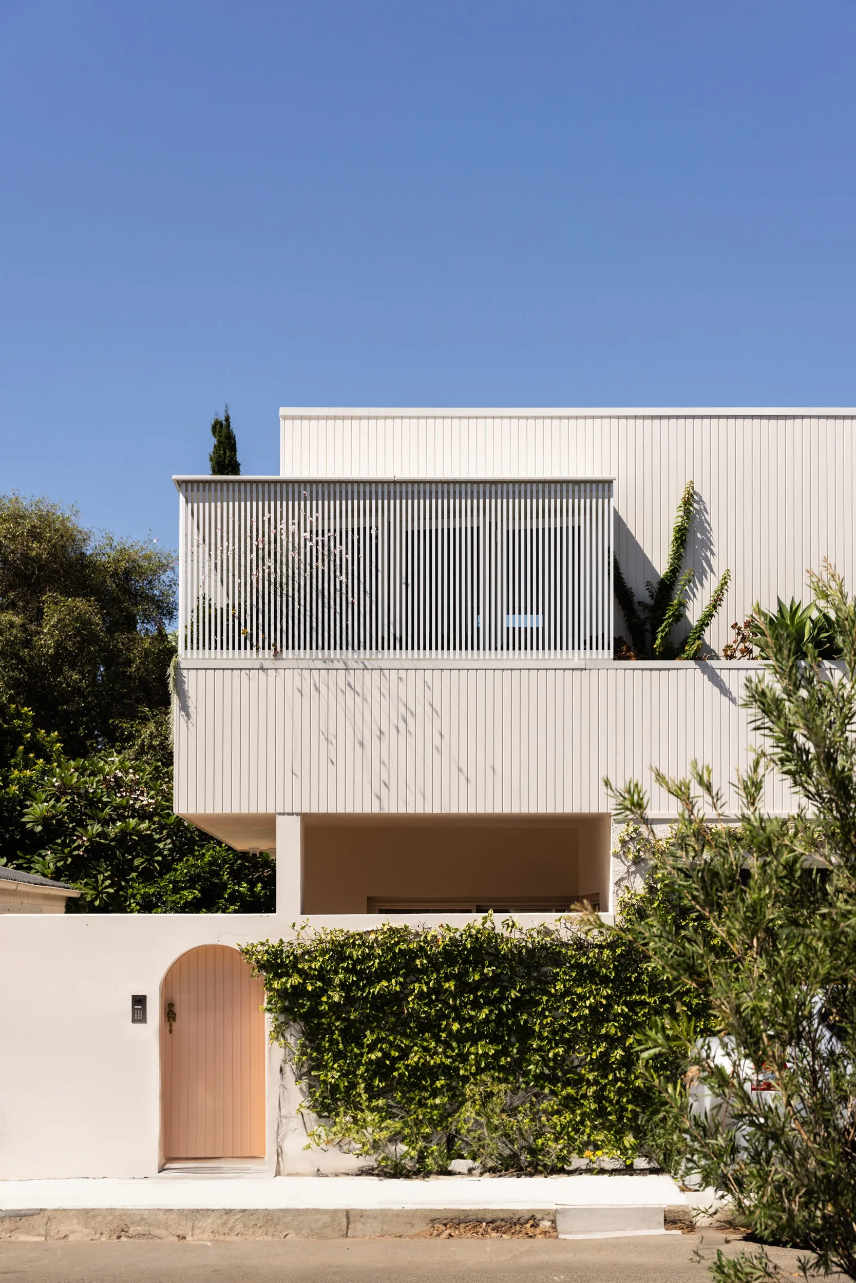 The exterior of a modern home painted in a soft pink hue