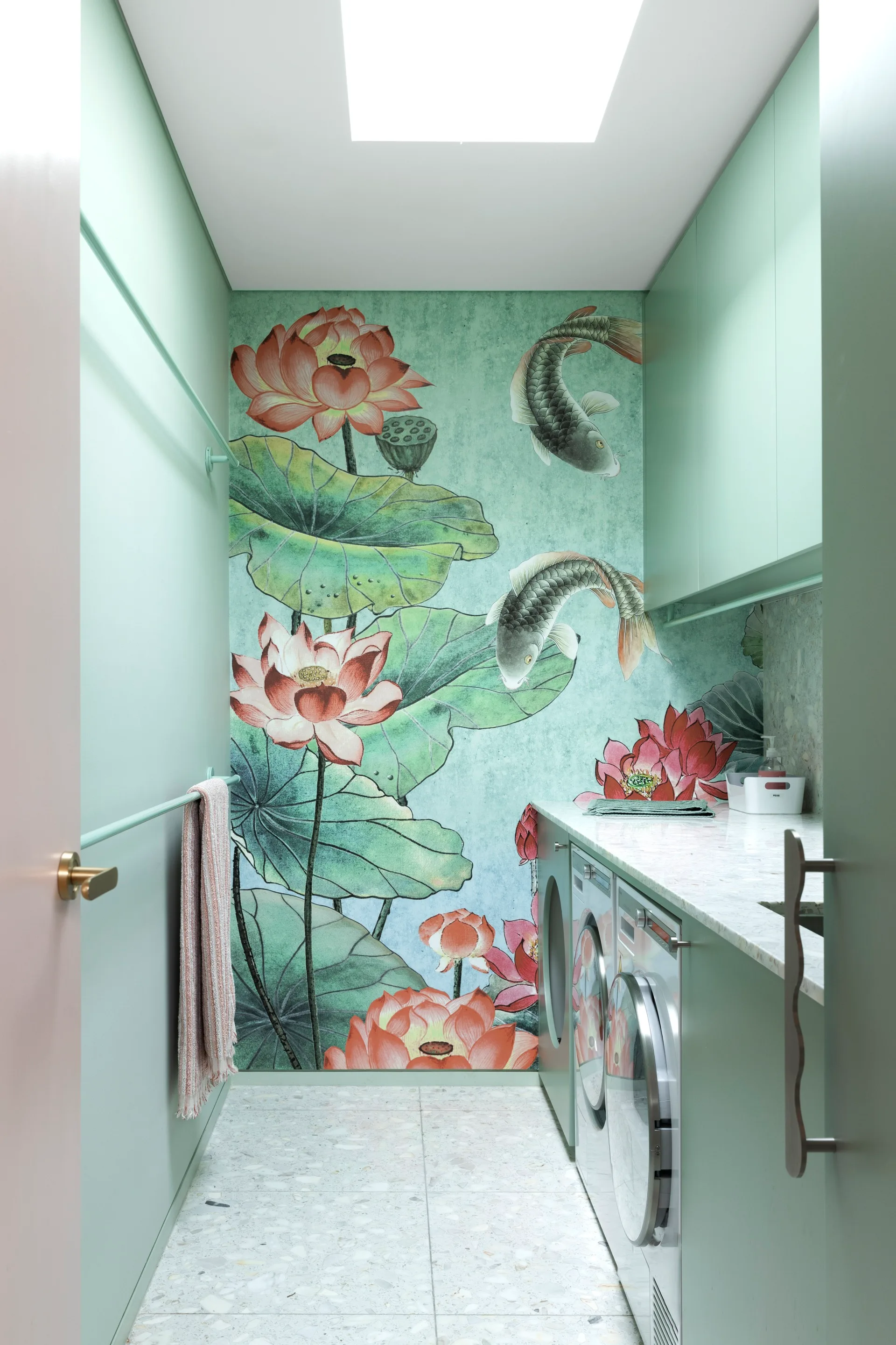 A mint coloured laundry with a feature wall covered in a fish and flower-print wallpaper