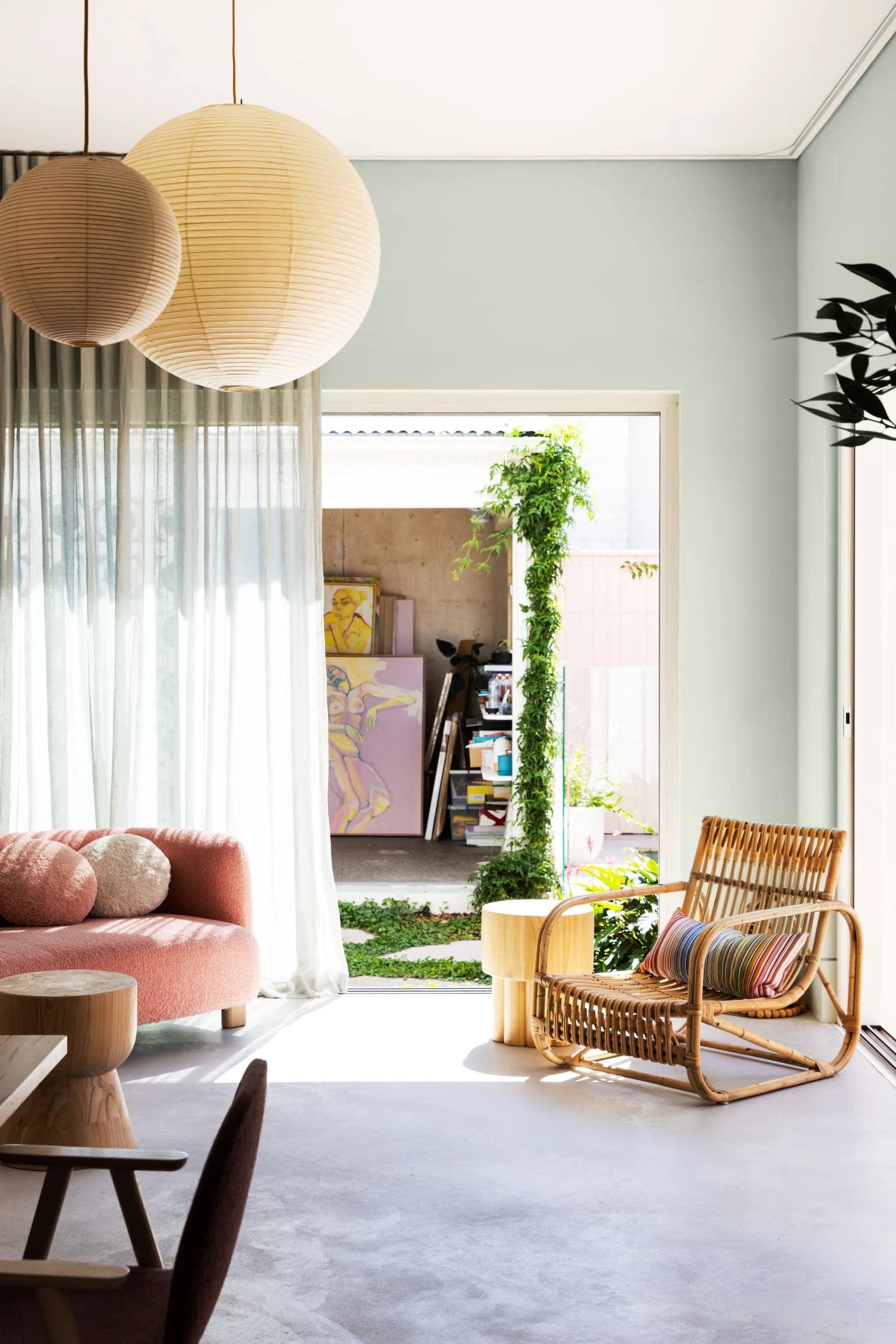 A room with concrete flooring and a rattan armchair