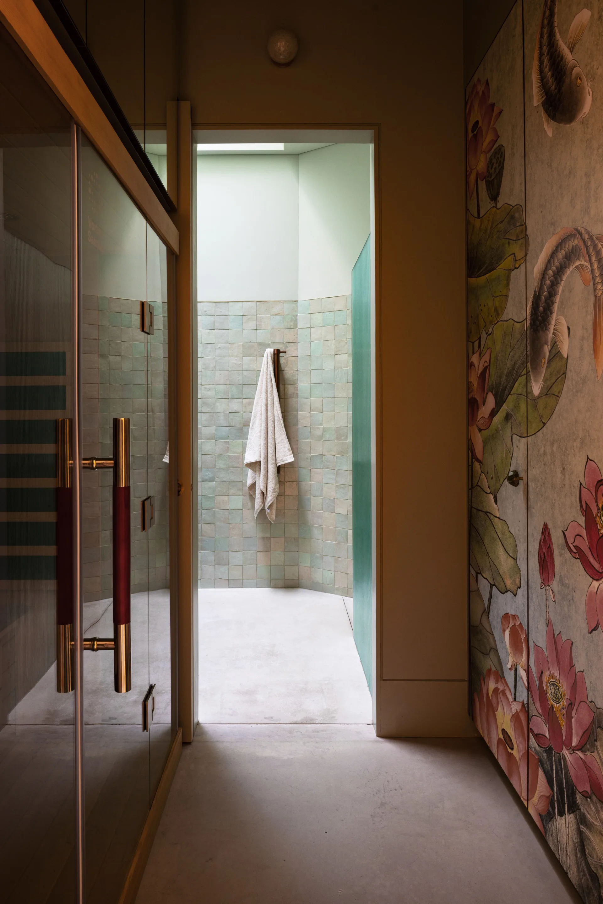 A hallway leading to a pastel green bathroom