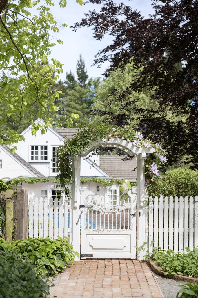 A white fence and gate covered in greenery