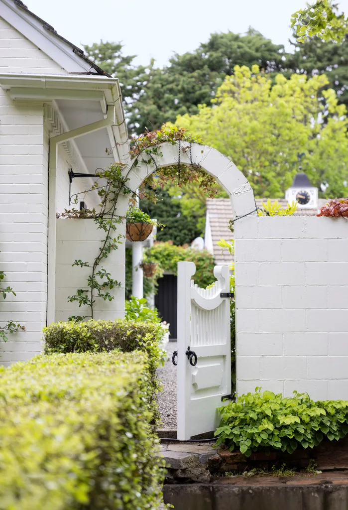 Side gate of a white homestead surrounded by trees