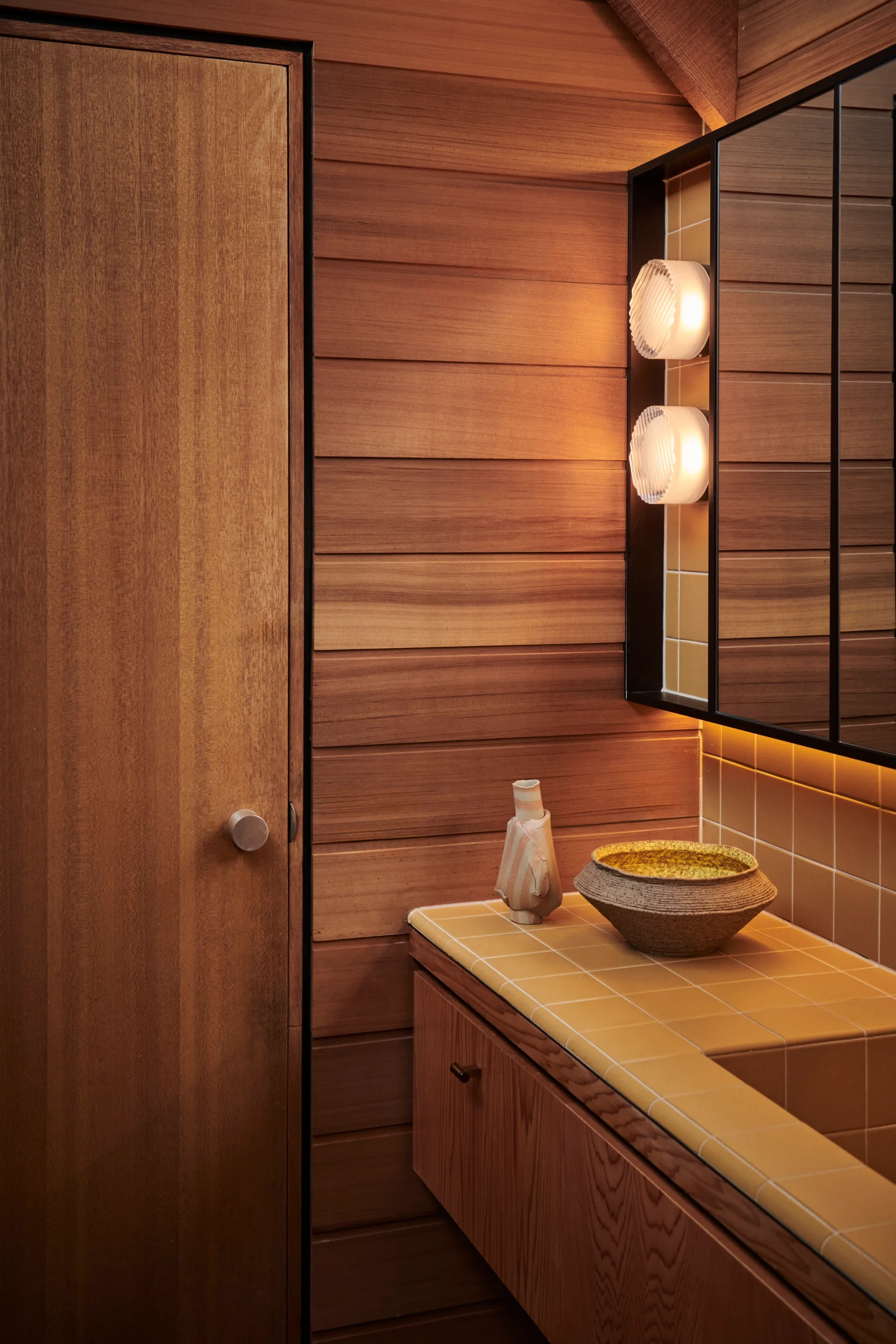 A timber-clad bathroom with mustard-coloured tiles