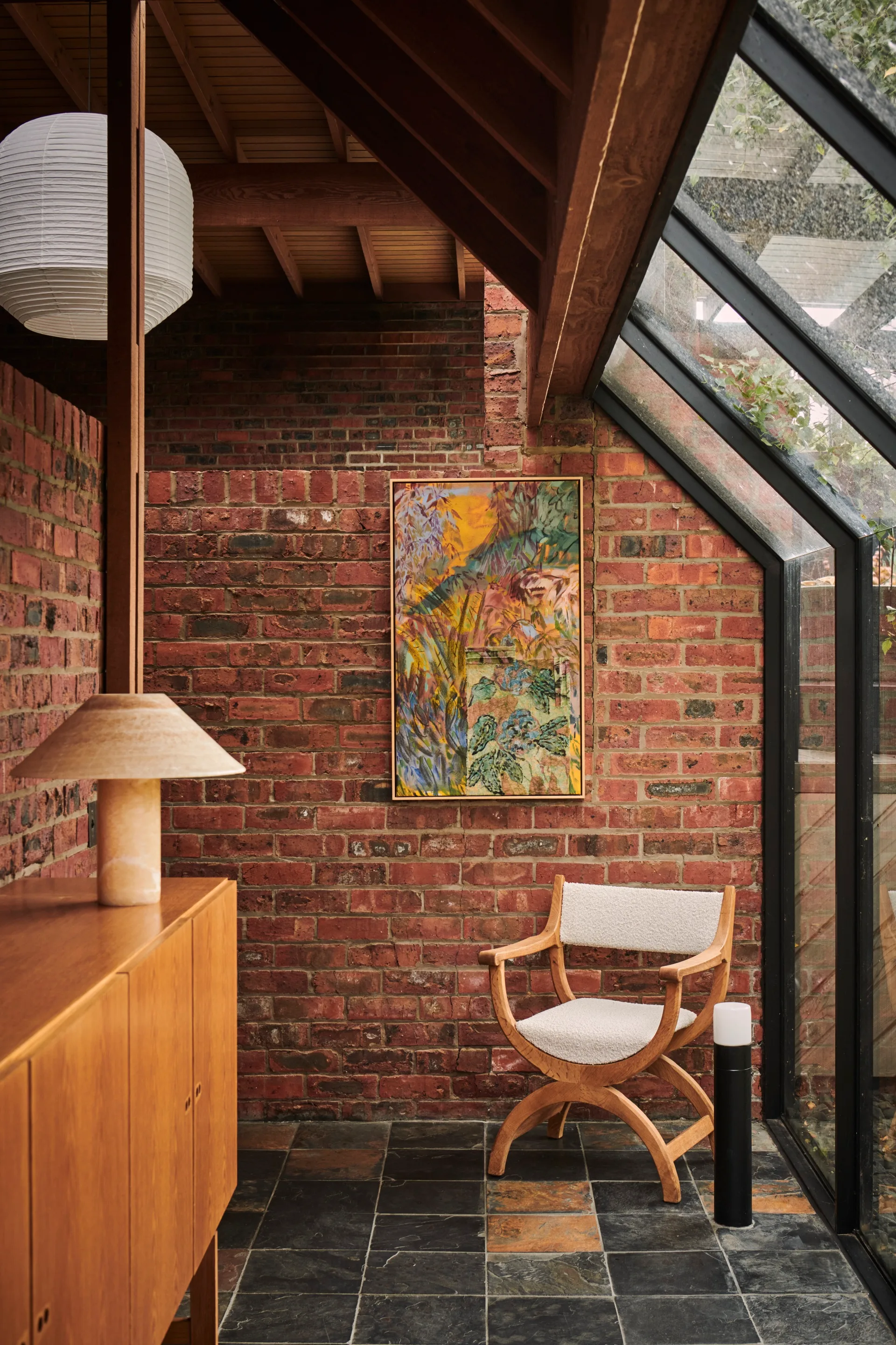 An atrium with exposed red brick walls and a timber chair