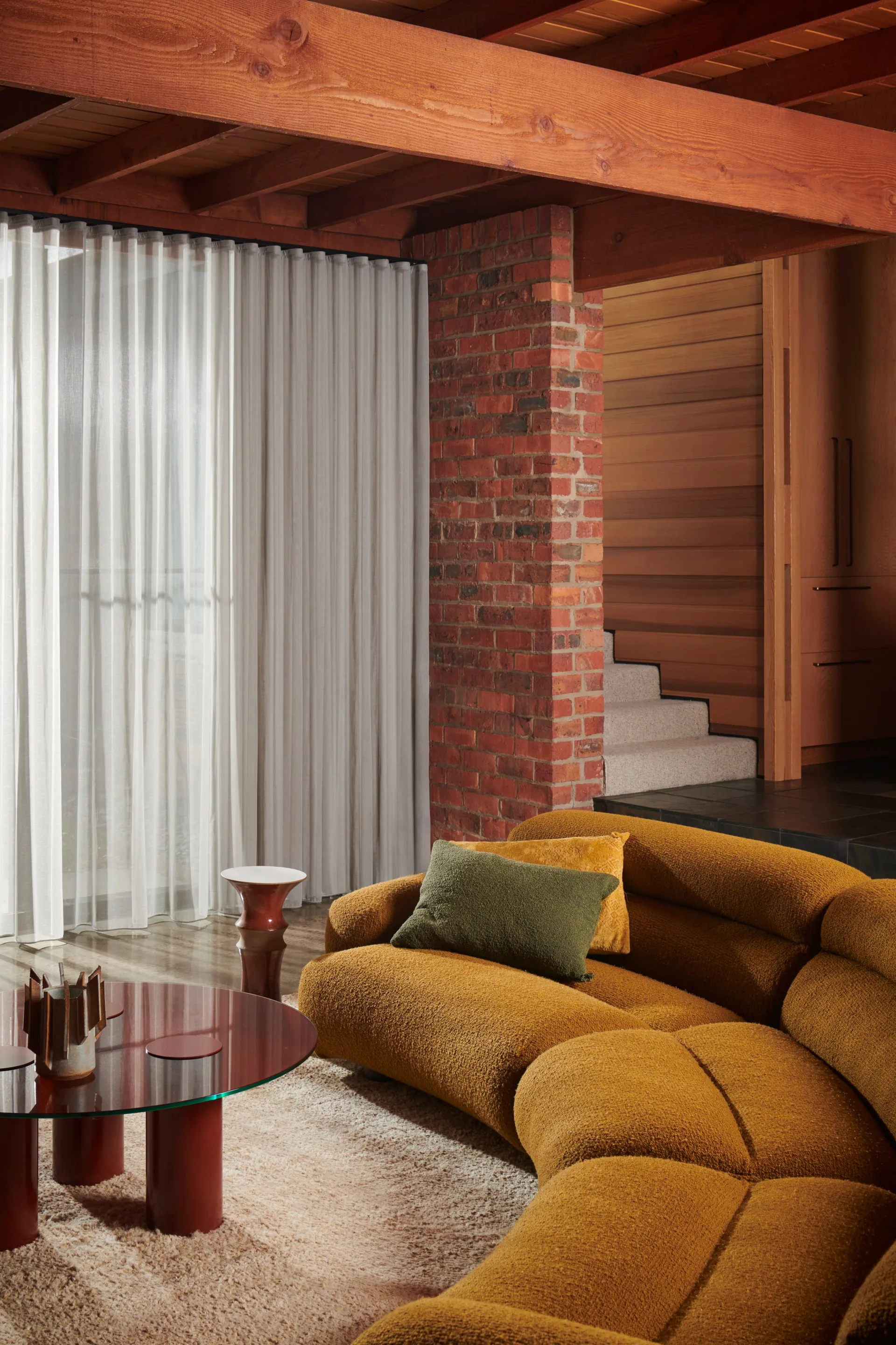 A curved mustard-olive-coloured couch in a cosy living room