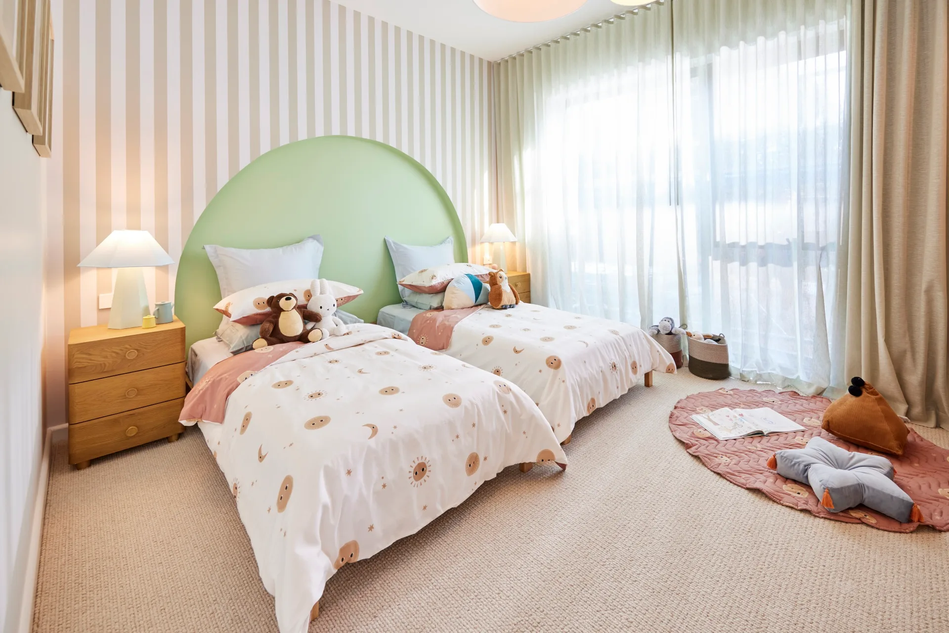 A kids bedroom with two single beds, striped feature wall and a green curved wall detail 
