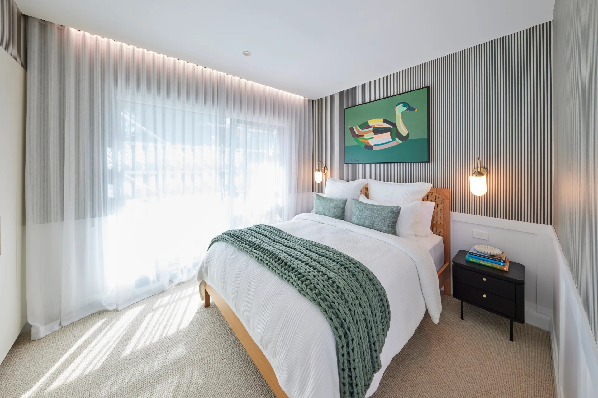 Jesse and Paige's guest bedroom with striped wallpaper a bed with white bed linen and a framed painting of a duck