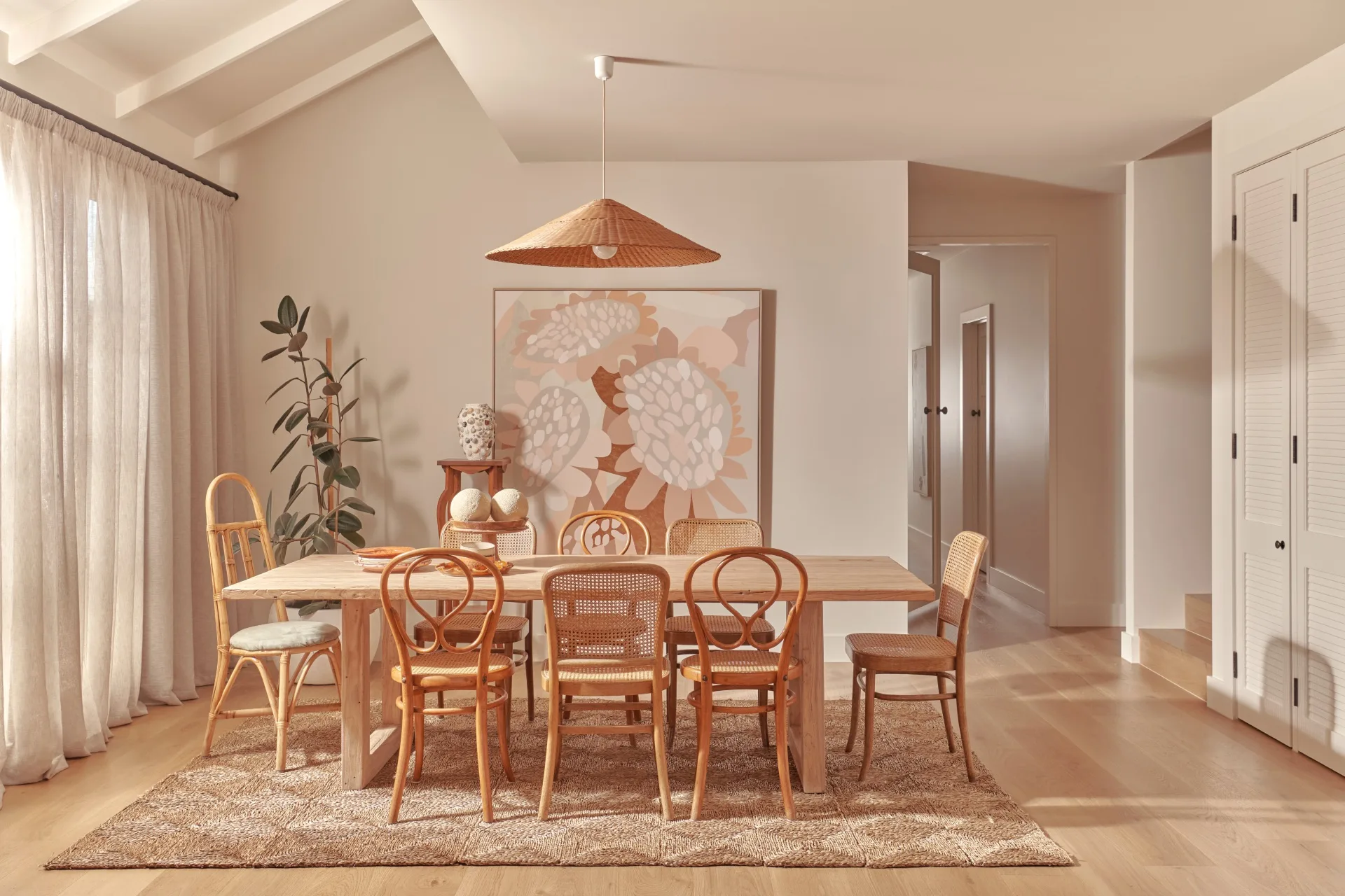 A large dining area with varying rattan chairs and a rattan pendant light