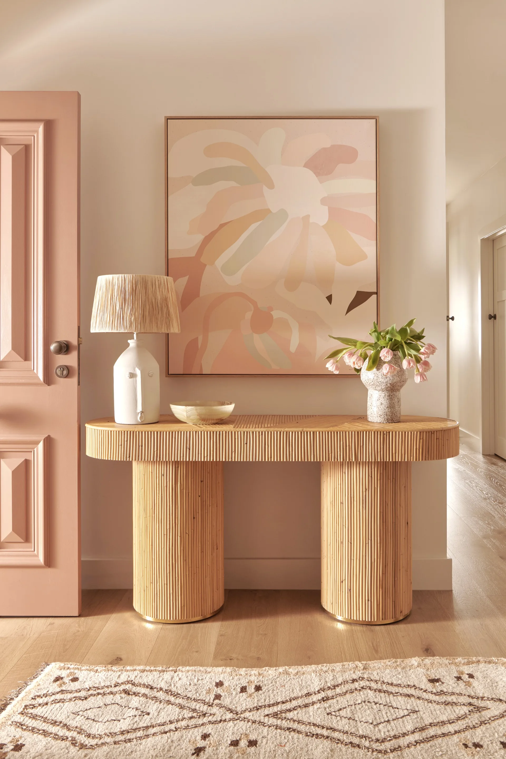 A rattan side table in a neutral-toned hallway