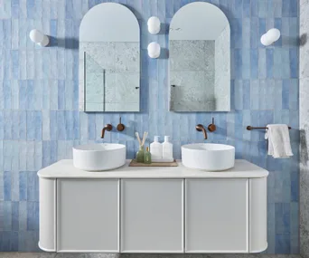 the block 2024 kristian and mimis blue tiled bathroom with white vanity and arched mirrors