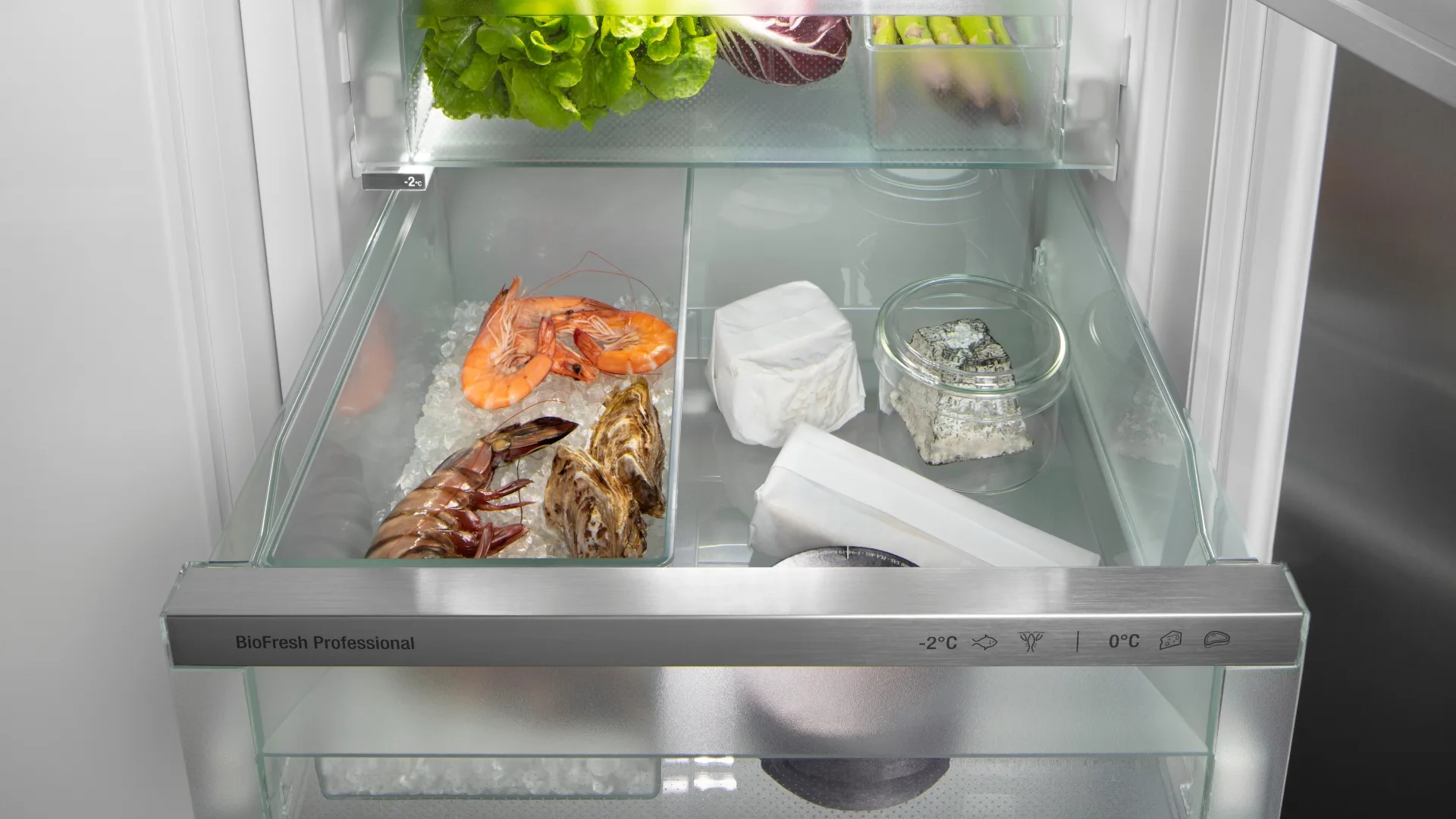 Open fridge door with lobster, prawns and cheeses