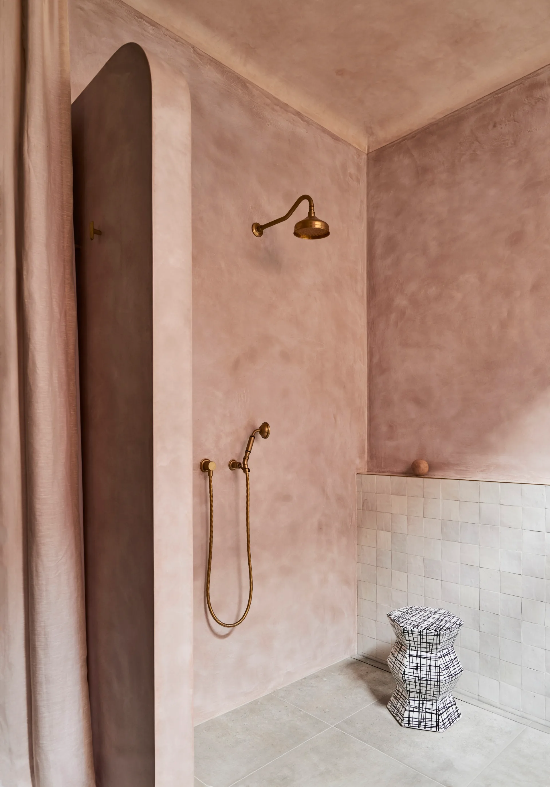 Pink microcement walk in shower with white zellige tiles and brass tapware