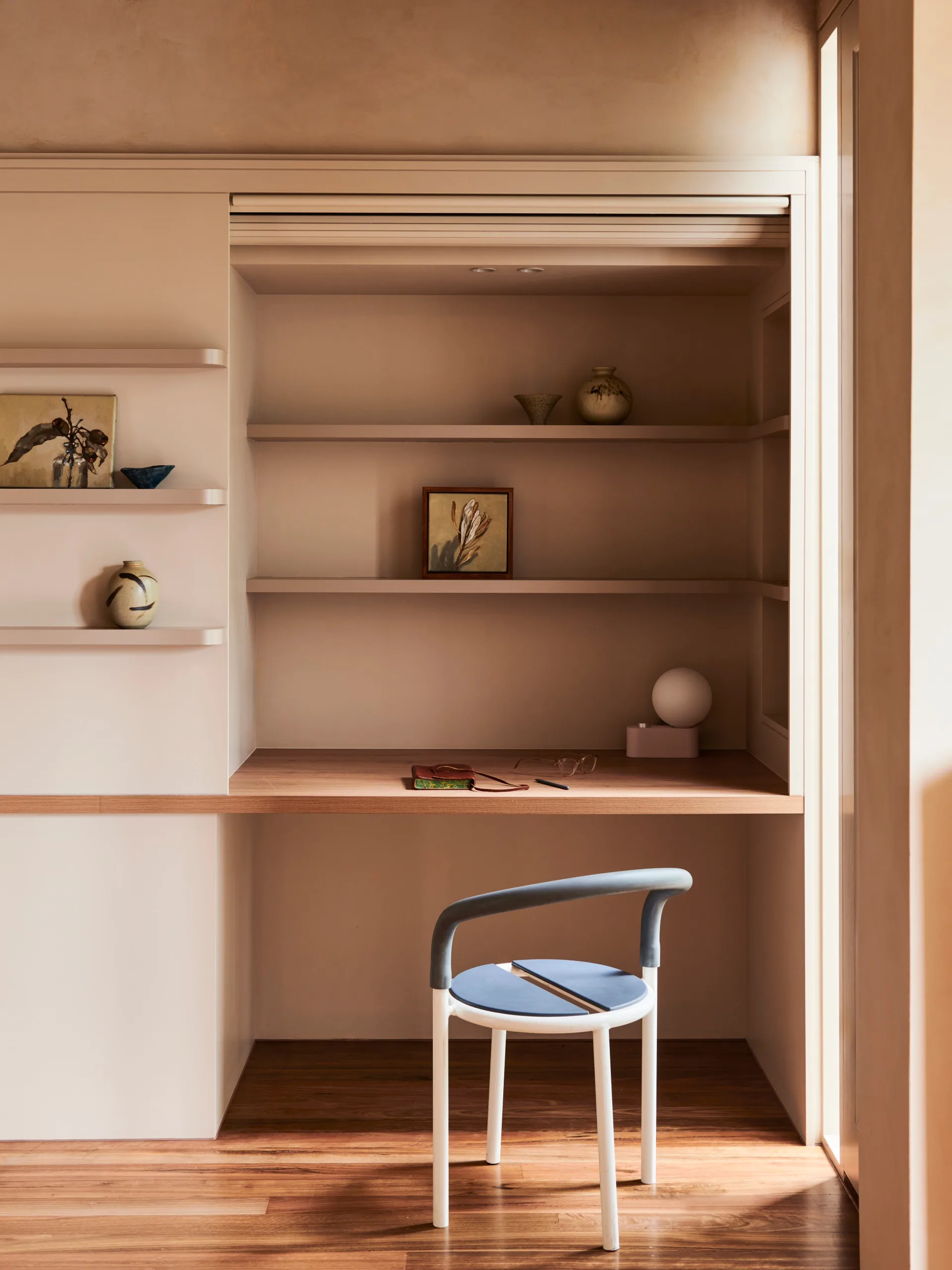 A study nook with floating shelves and a blue chair.