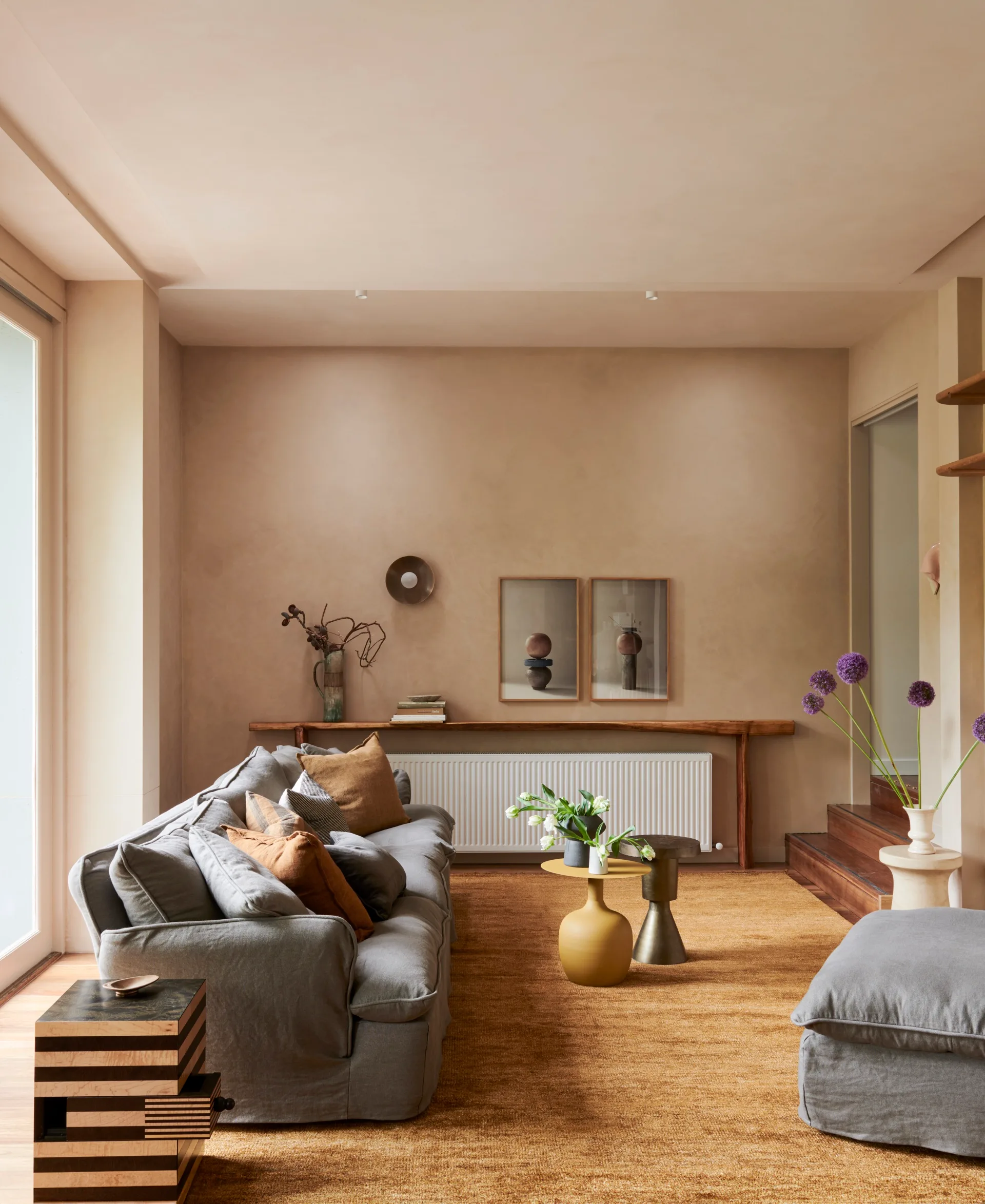 A sunken living room with a soft grey sofa and wheat coloured rug.