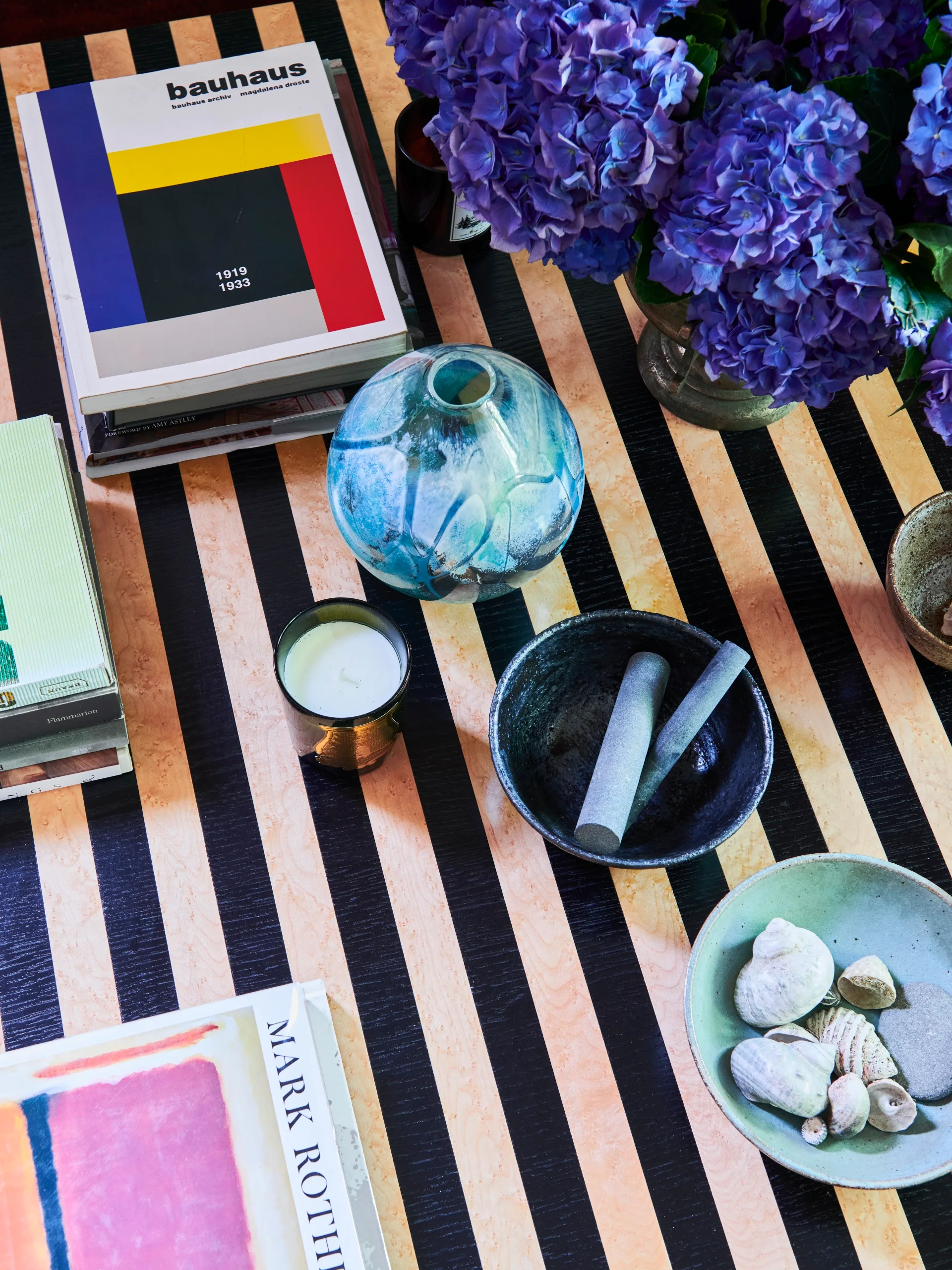 A striped coffee table styled with groups of art books and various decorative objects.