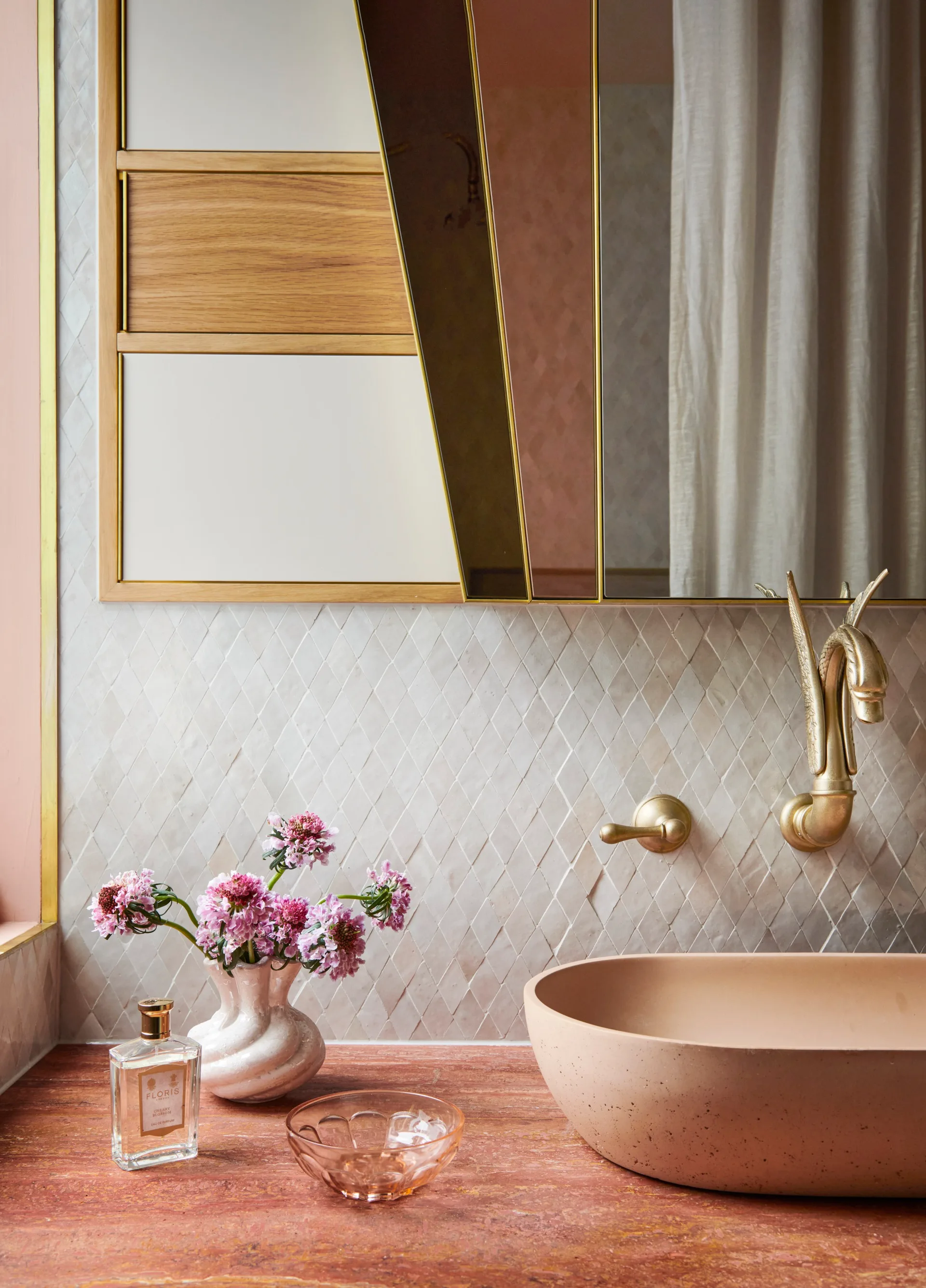 Brass Swan-shaped tapware sits above a pink concrete basin a pink microcement ensuite bathroom
