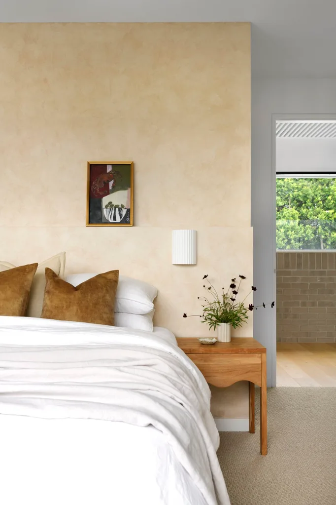 A neutral-toned bedroom with white bedding and lime washed walls