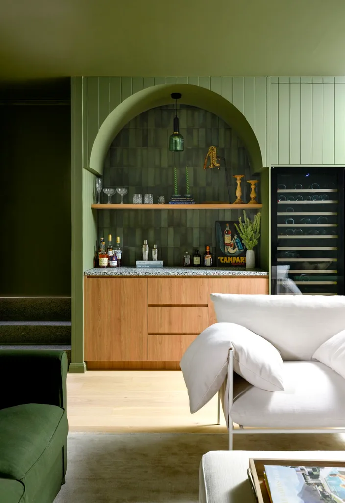 A green built-in bar with an arched detail with a white lounge