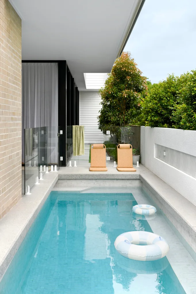 A lap pool with floaty rings and two small orange sun loungers
