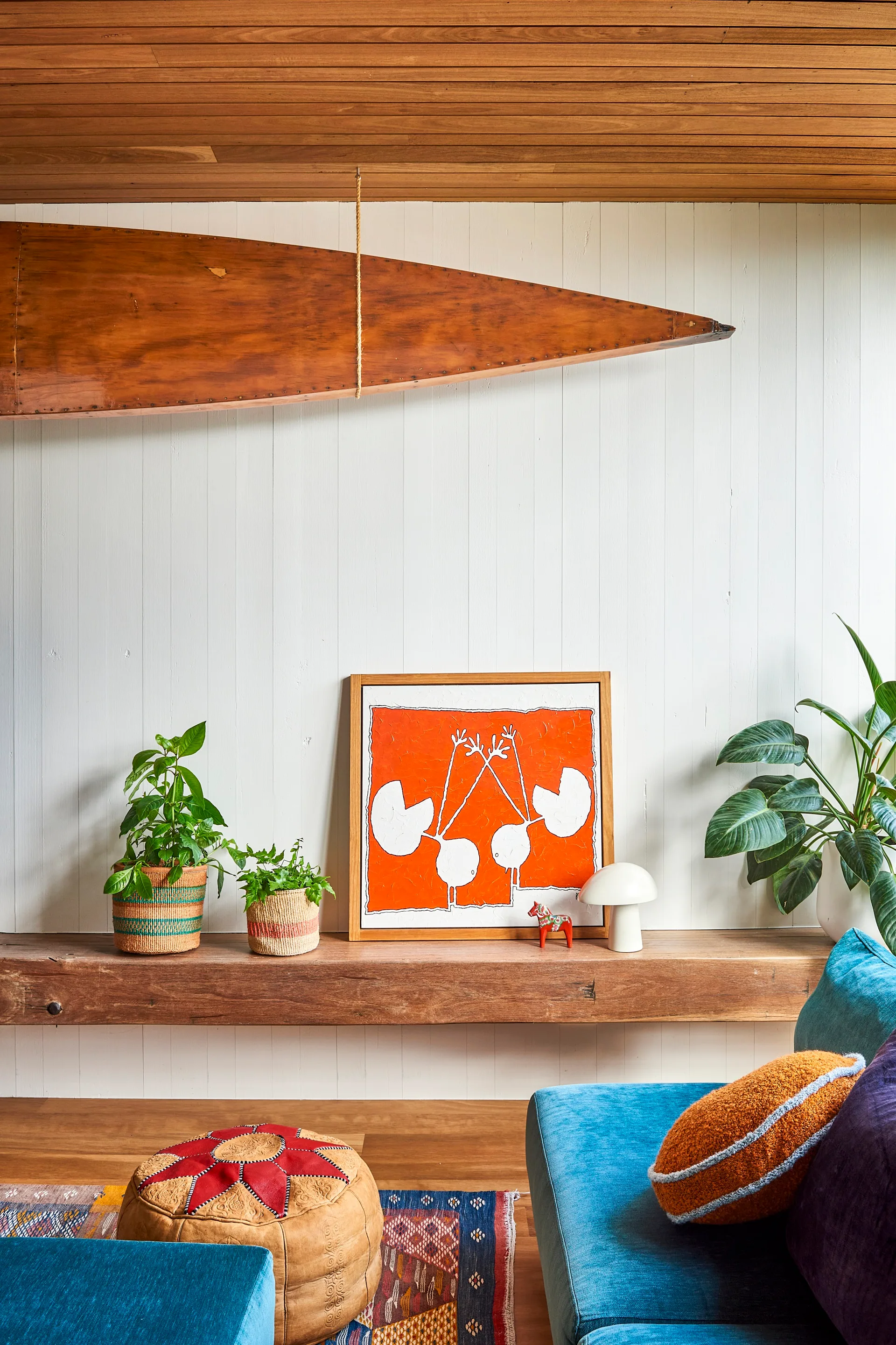 A floating timber shelf in a living area with a blue couch and indoor plants