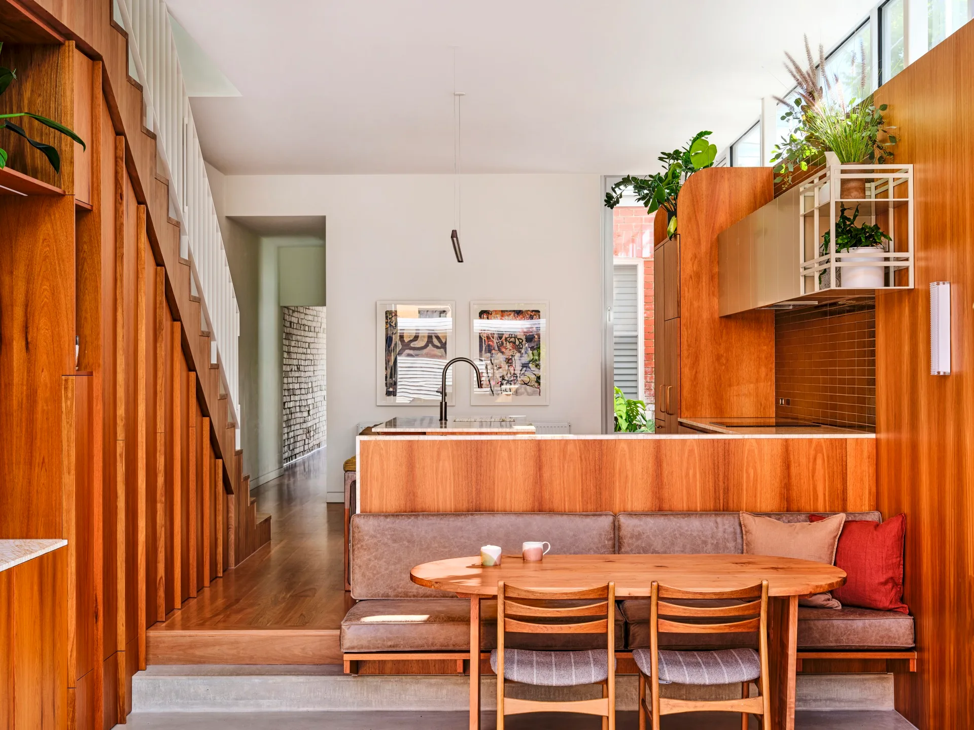 An open-plan living area and kitchen with timber floors and a banquette dining seat