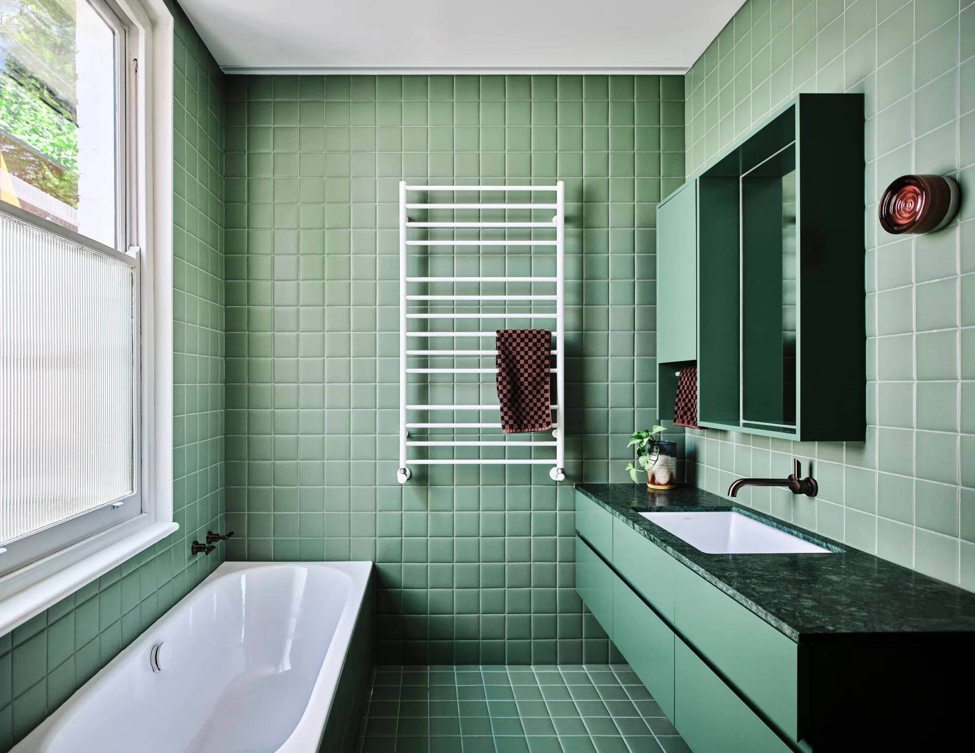 An all-green bathroom with a white towel rail