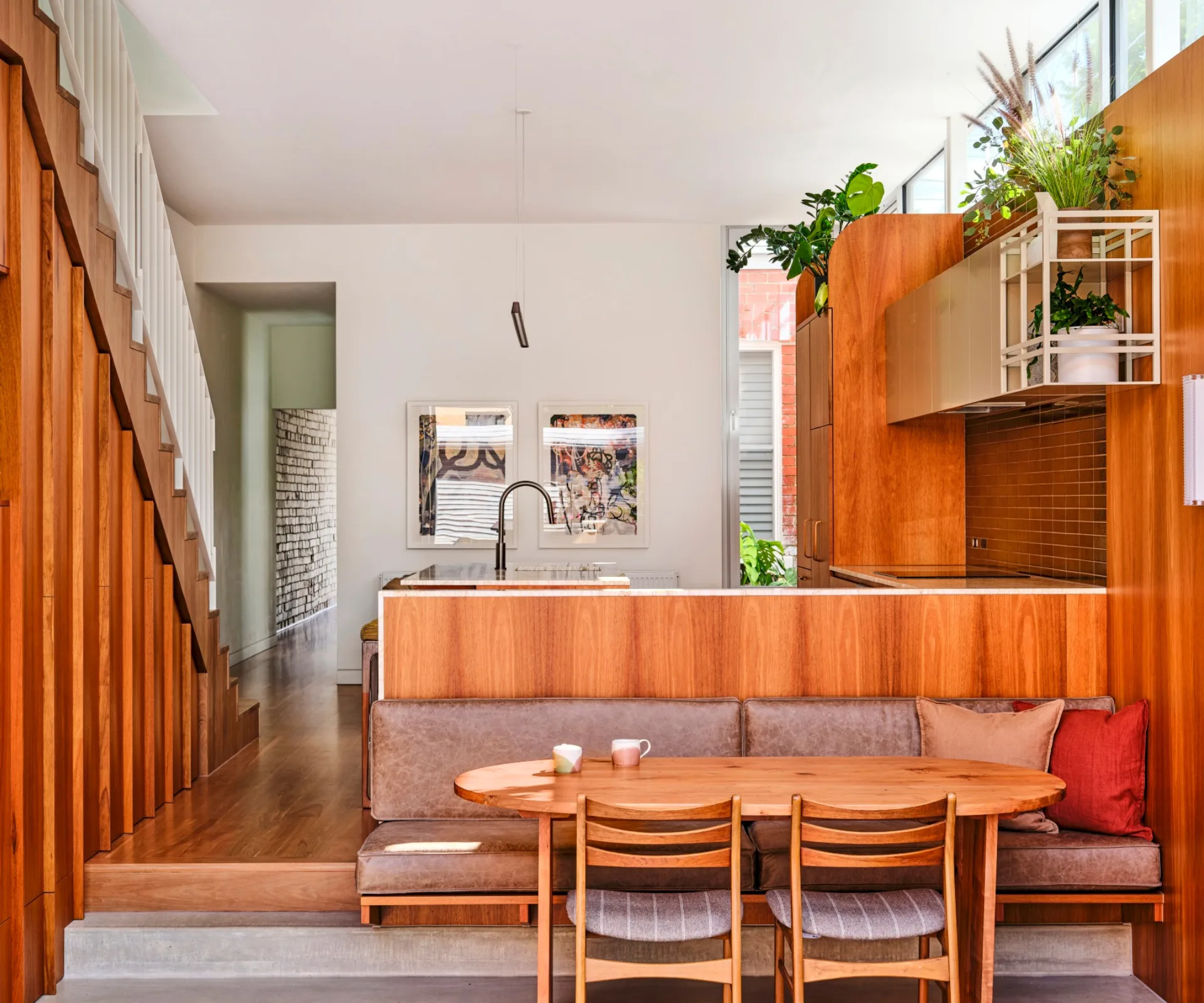 An open-plan living area and kitchen with timber floors and a banquette dining seat