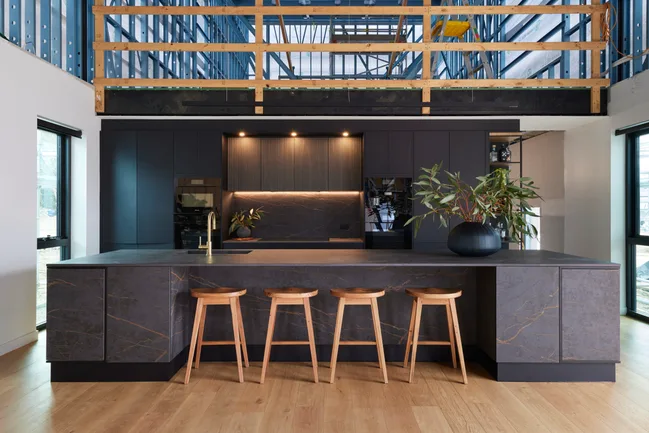 A large black kitchen with timber stools