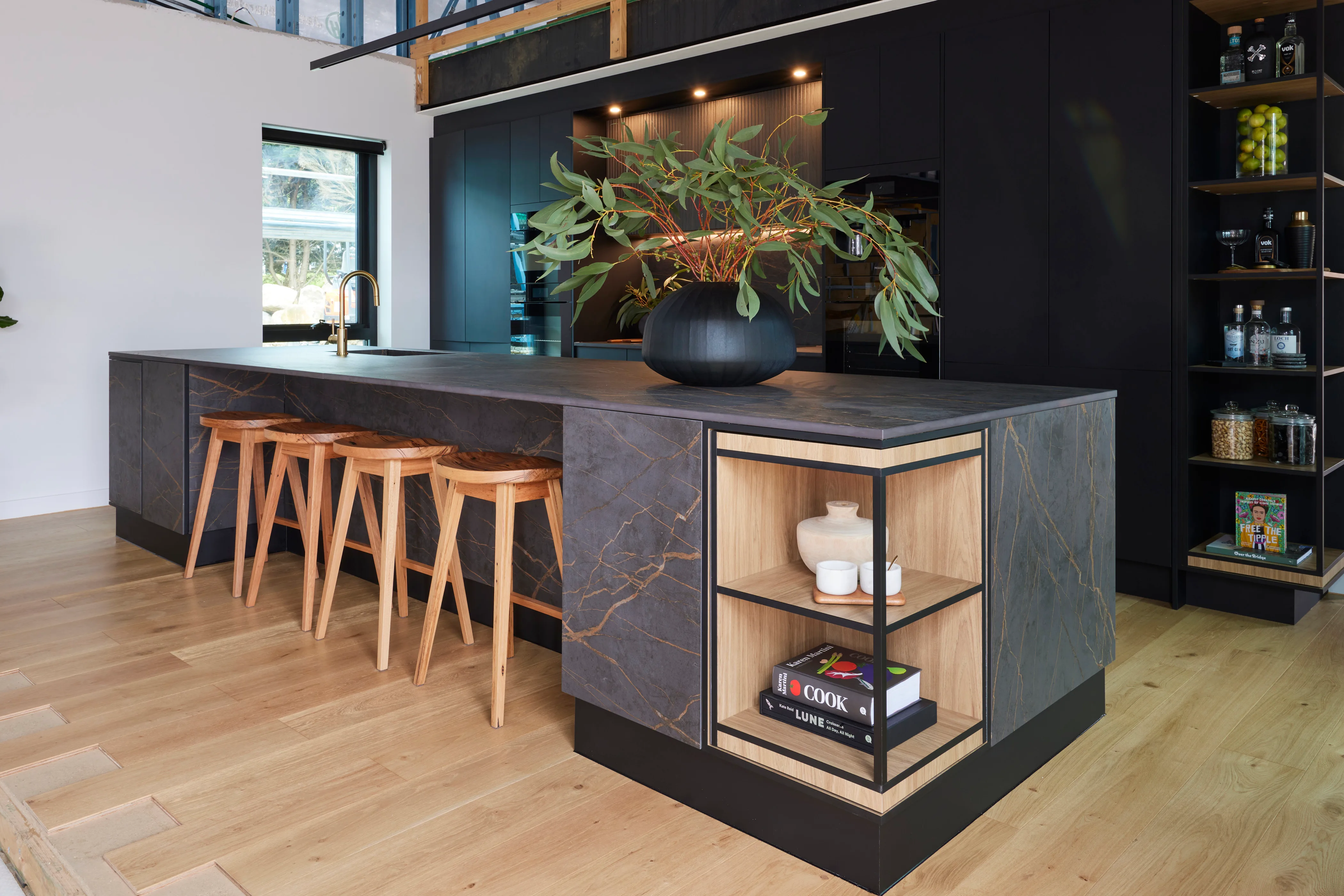 A black kitchen with a timber shelving detail