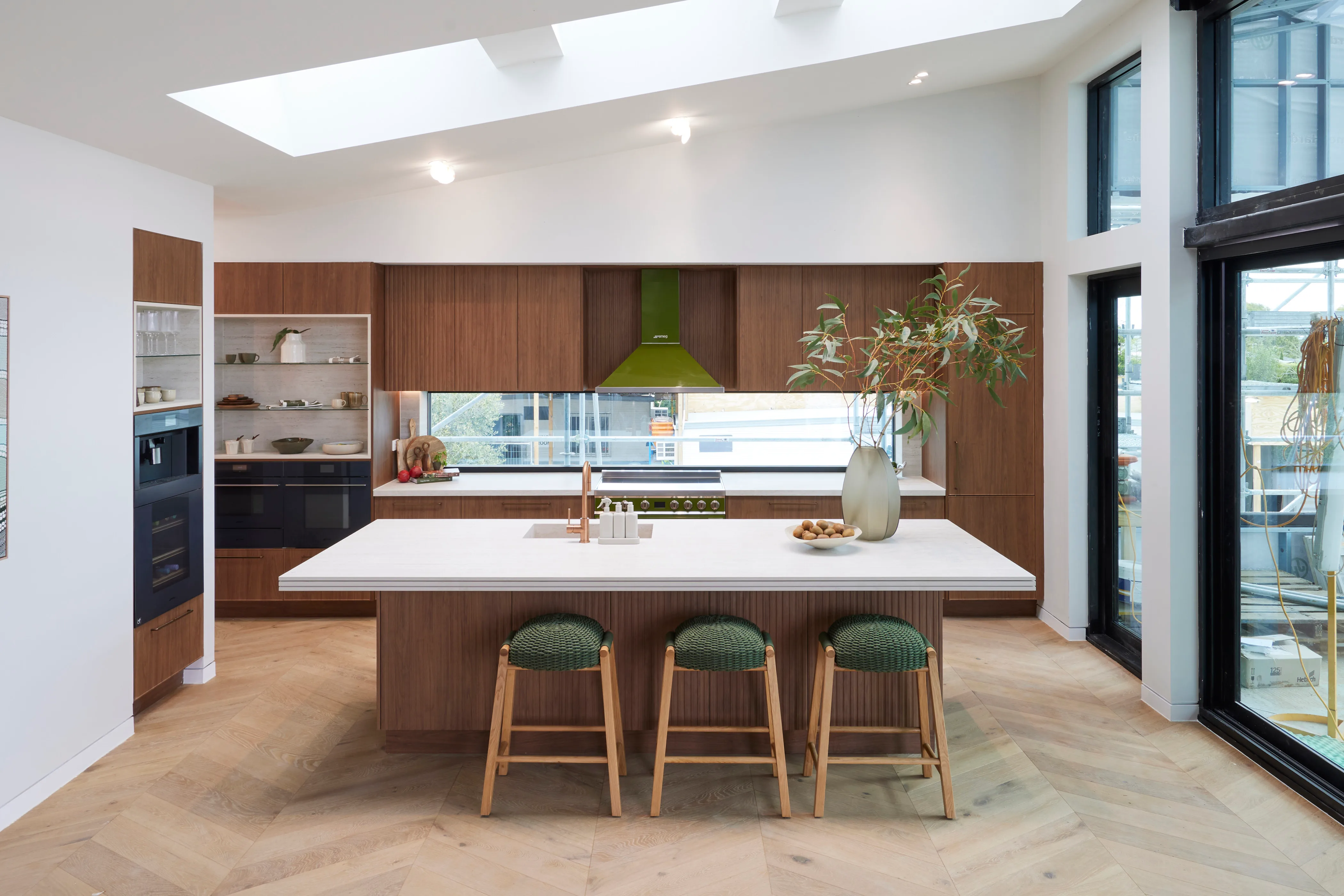 A contemporary kitchen with dark timber cabinetry and a white island bench