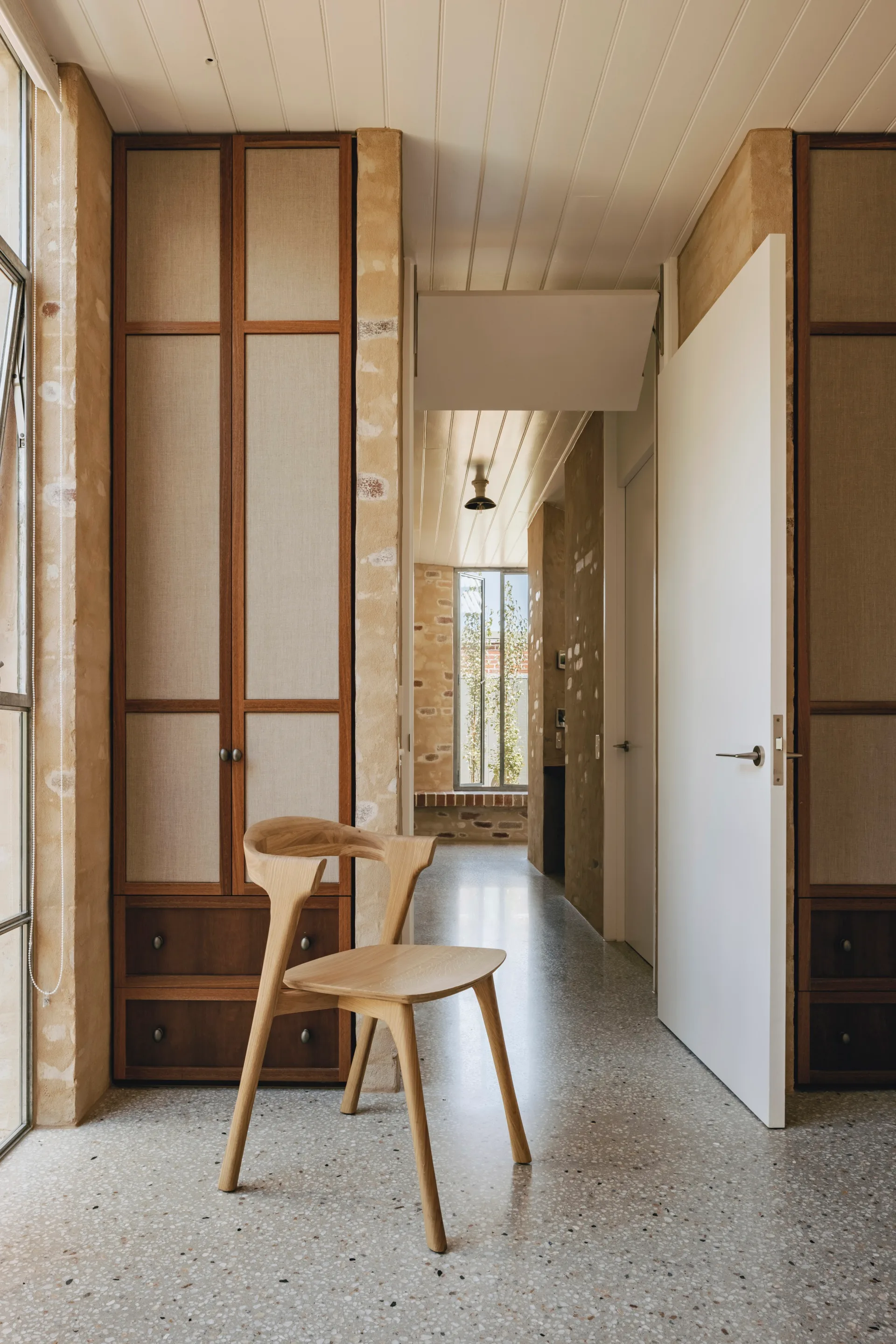 A light-filled hallway with a timber chair
