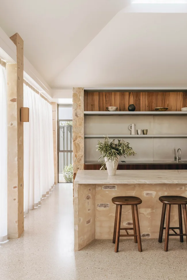 A contemporary kitchen with stone elements and stainless steel benchtops