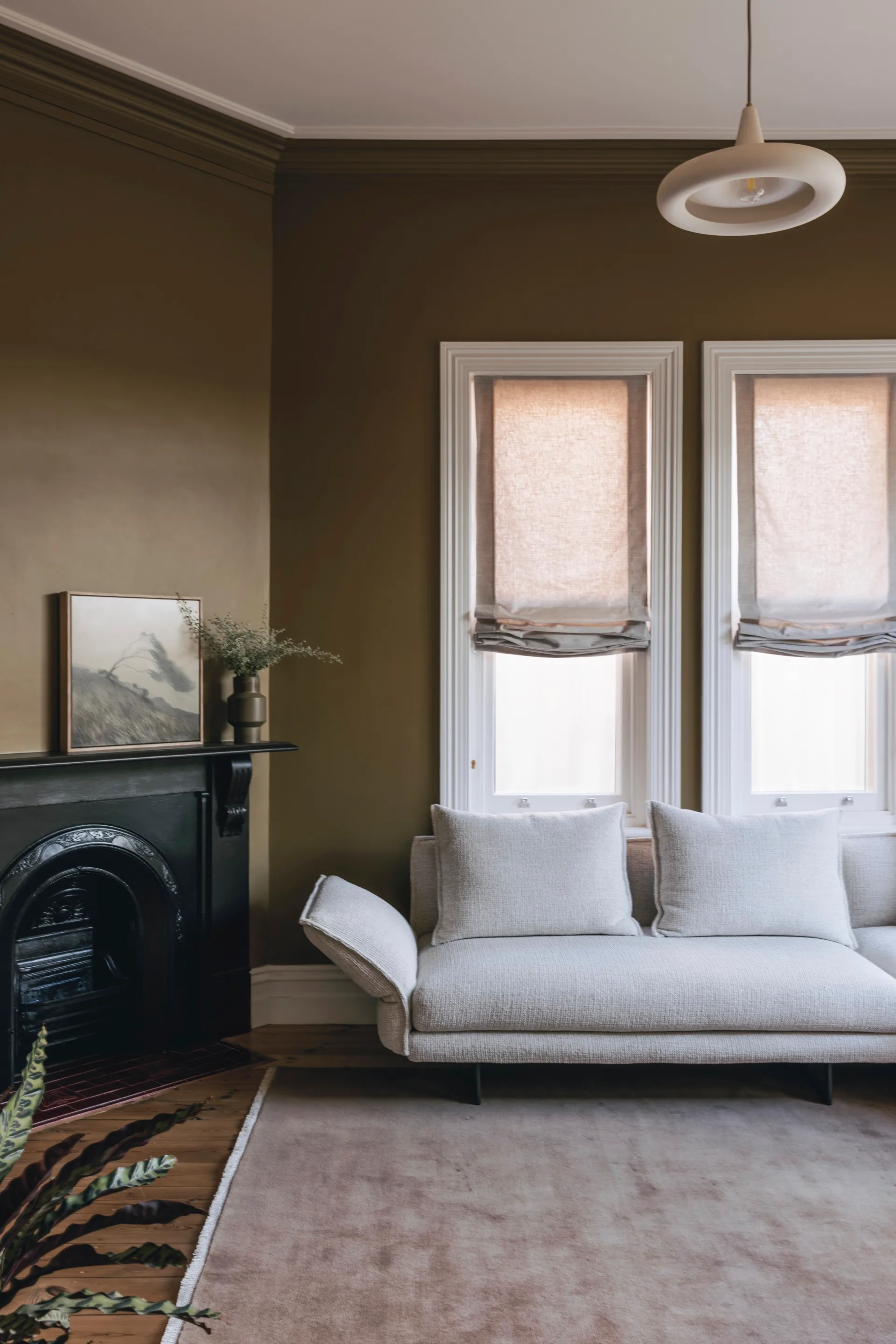 A lounge area with a white couch and statement pendant light