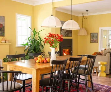 A butter yellow dining and living space with pendant lights and a country feel