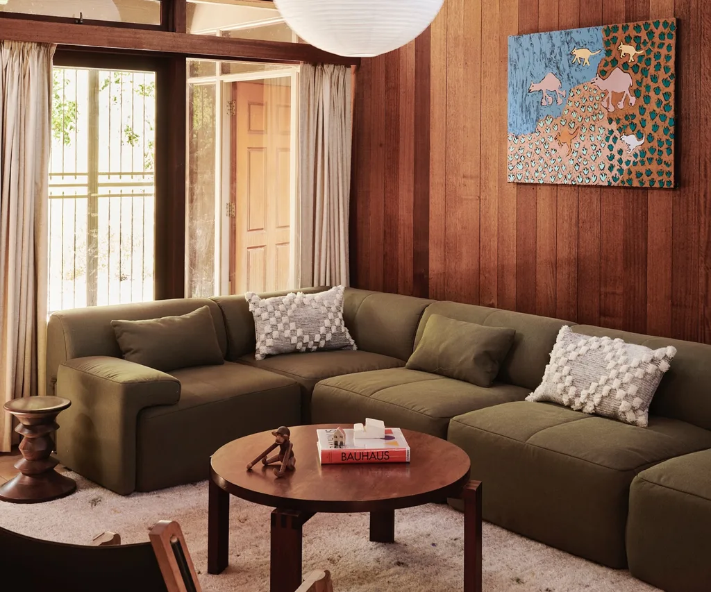 A lounge room with timber panelling and a green Eva sofa